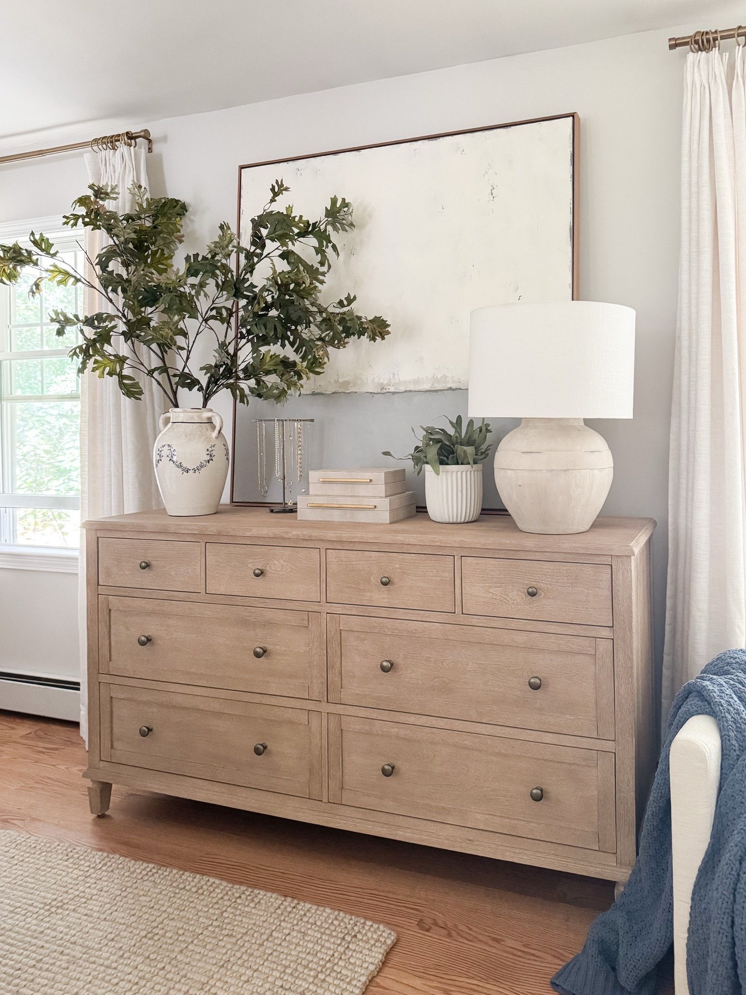 Light wood dresser styled with oversized neutral artwork, ceramic table lamp, stacked decorative boxes, and greenery in a white vase. Balanced, minimal coastal styling for a serene bedroom. 
dresser decor, bedroom dresser styling, oversized wall art, neutral artwork, decorative boxes, ceramic lamp, greenery vase, coastal bedroom decor, light wood furniture, minimalist home decor, organic modern bedroom, styled surfaces, sherri calnan home

#LTKHome