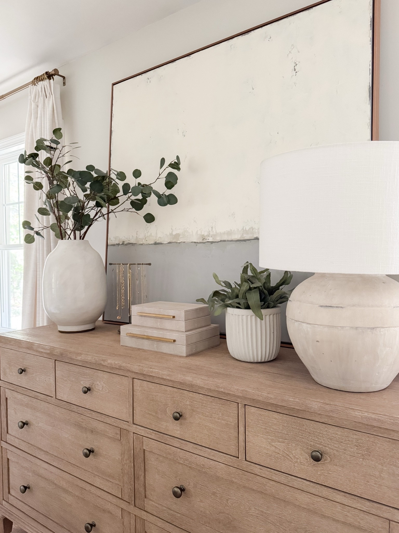 Light wood dresser styled with oversized neutral artwork, ceramic table lamp, stacked decorative boxes, and greenery in a white vase. Balanced, minimal coastal styling for a serene bedroom. 
dresser decor, bedroom dresser styling, oversized wall art, neutral artwork, decorative boxes, ceramic lamp, greenery vase, coastal bedroom decor, light wood furniture, minimalist home decor, organic modern bedroom, styled surfaces, sherri calnan home

#LTKHome