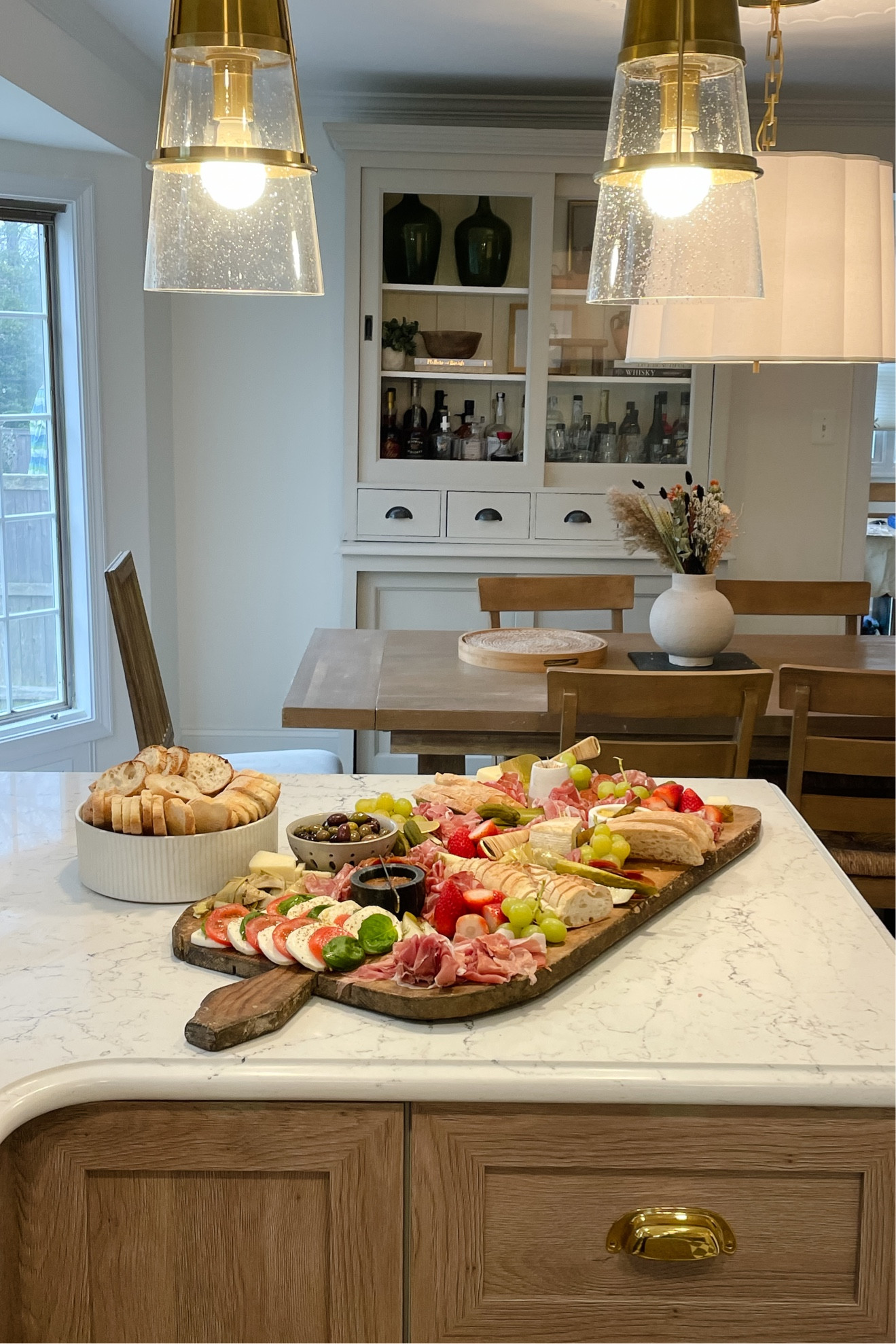 Pendant lighting over peninsula paired with Visual comfort chandelier ✨ 

Charcuterie board, berry bowl, cheese knives and marble bowl and knife all from www.peonyandolive.com

#LTKhome