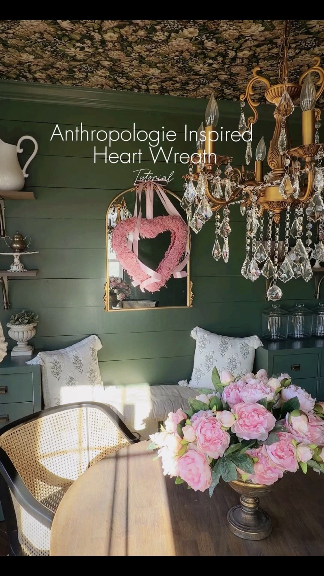 Anthropologie-inspired heart wreath DIY using reindeer moss, a heart wreath form, and simple craft supplies. This moss wreath is layered on a gold vintage inspired mirror in my dark green breakfast room, an old world inspired space with floral peel and stick wallpaper on the ceiling and a cozy, collected look. Shop the heart wreath form, reindeer moss, mirror, cane back chairs and home decor. 