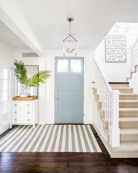 Our Omaha entryway decorated for summer with a white glossy raffia cabinet, blue and cream striped rug, lantern pendant light, “It Is Well” canvas art, tall thin black framed mirror, faux palm leaves and a paint dipped vase.

#ltkstyletip #ltkunder50 #ltkunder100    coastal entry decor, blue and white decor, foyer tables

#LTKSeasonal #LTKhome #LTKsalealert #LTKSeasonal #LTKsalealert #LTKhome #LTKhome #LTKsalealert #LTKSeasonal