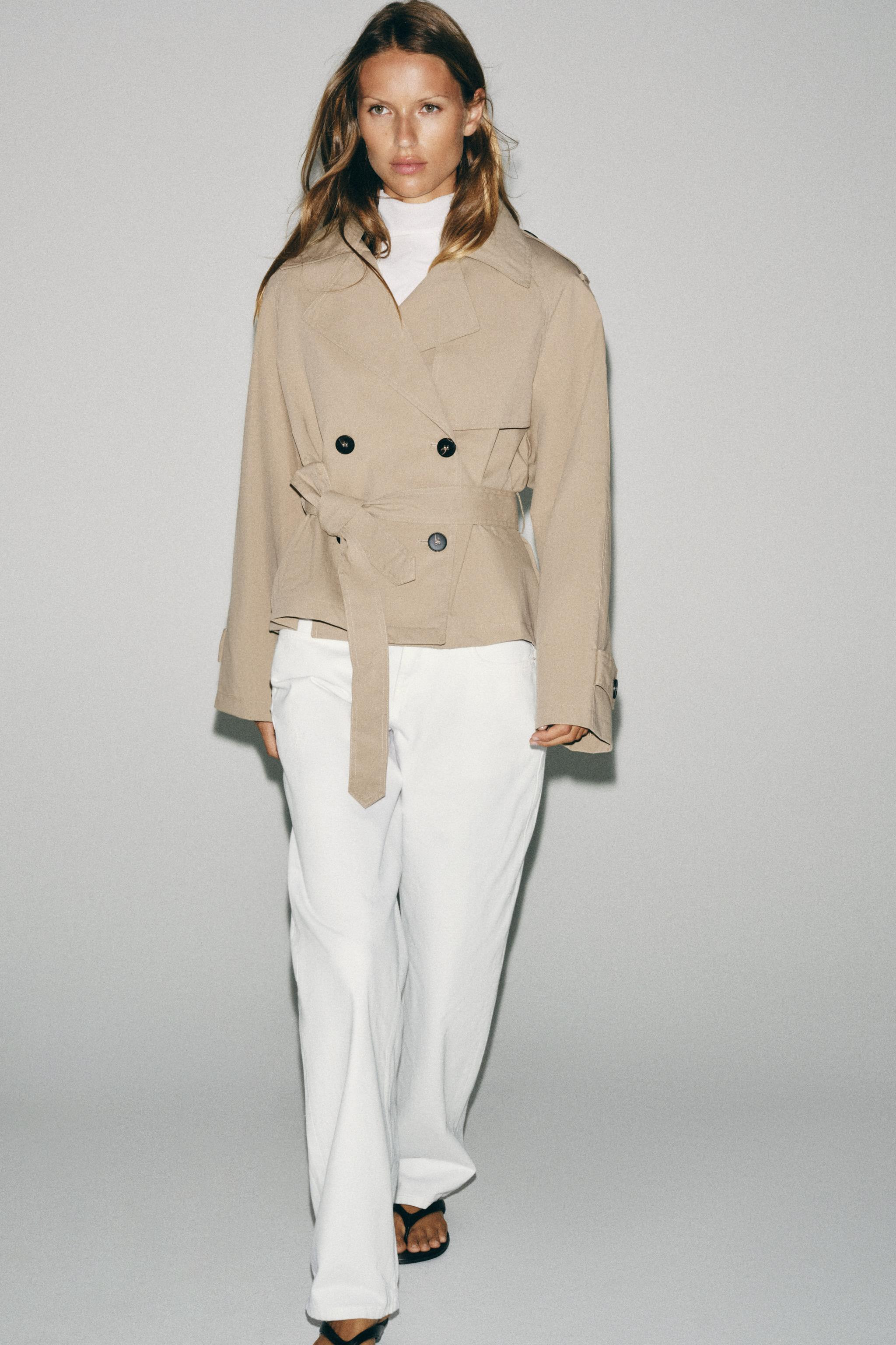 Short trench-style jacket with a lapel collar and long sleeves with shoulder pads. Features tab a... | Zara US