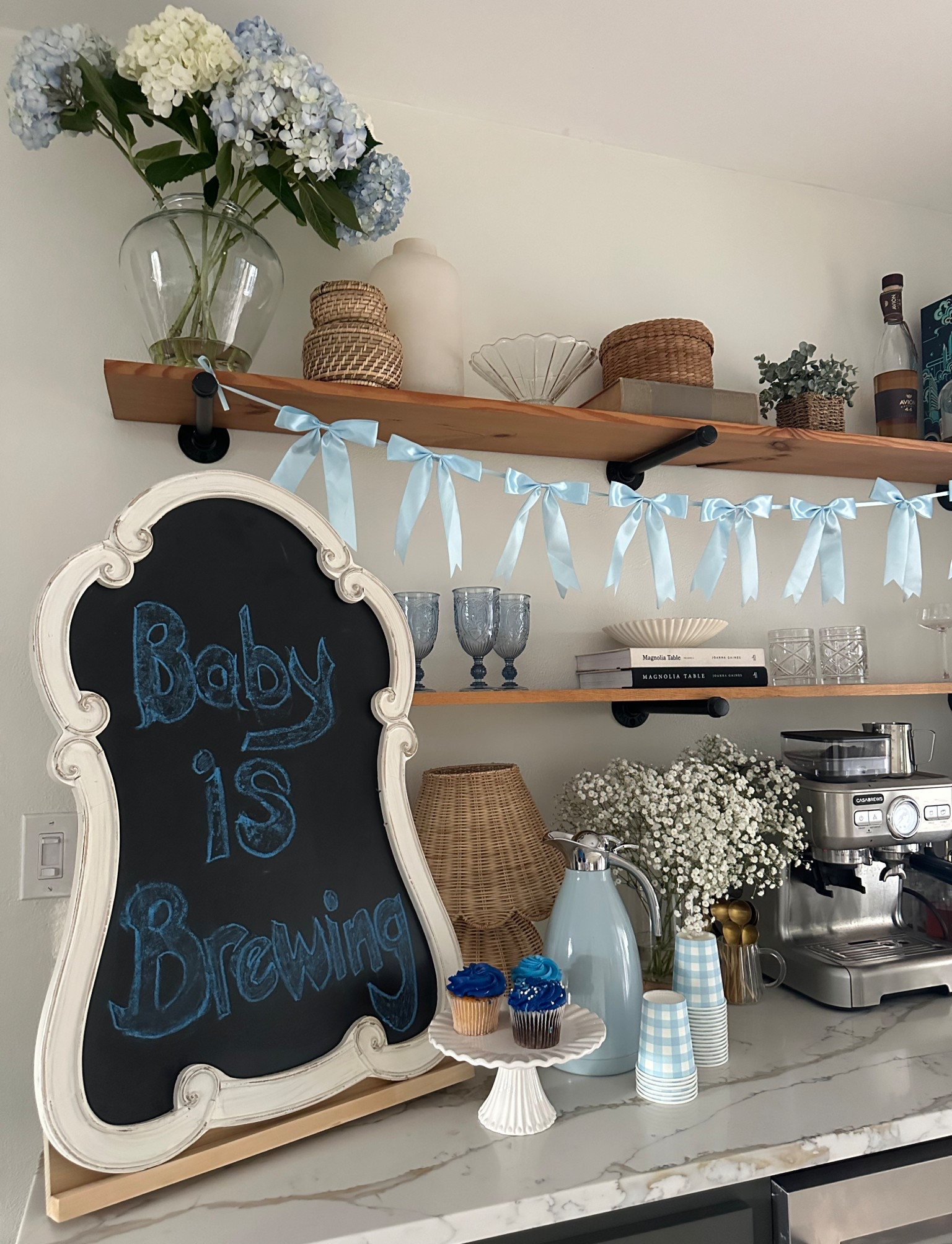 Baby shower coffee bar
We added this vintage chalkboard and the cutest little baby blue bow garland to our shelves. Mixed in these blue vintage glasses and fun gingham coffee cups. This would be great for a wedding or any special occasion.

Party decor 
Baby shower decor 
Baby boy 
Wedding decor
Home decor
Amazon home
Vintage 
Coffee 
Home bar 
Kitchen
Coffee Cart 
Baby shower inspo 
Baby blue 
Dusty blue
Flowers 
Hydrangeas 
Babies breath 
Espresso machine 
Baby is brewing 

#LTKBaby #LTKWedding #LTKBump