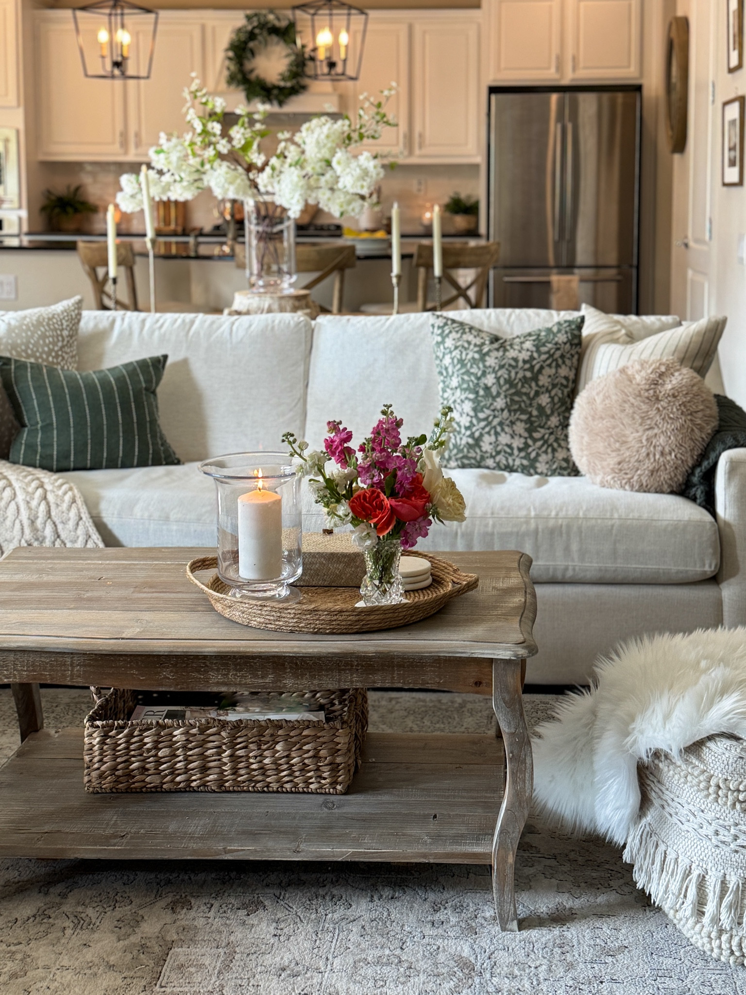Cozy neutral living room with fresh and faux florals, neutral and dark green pillows, French country style coffee table and textured pouf with faux fur 

Hurricane glass candle holder, cherry blossoms, basket tray, storage basket, neutral rug 




#LTKhome #LTKSeasonal