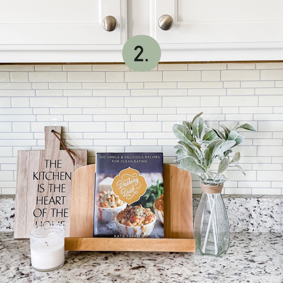Cookbook and cutting board kitchen counter styling.
Dashing Dish Cookbook
Cookbook stand 
Lambs ears stems
Glass vase 
Cutting board
Candle

#LTKhome #LTKunder50