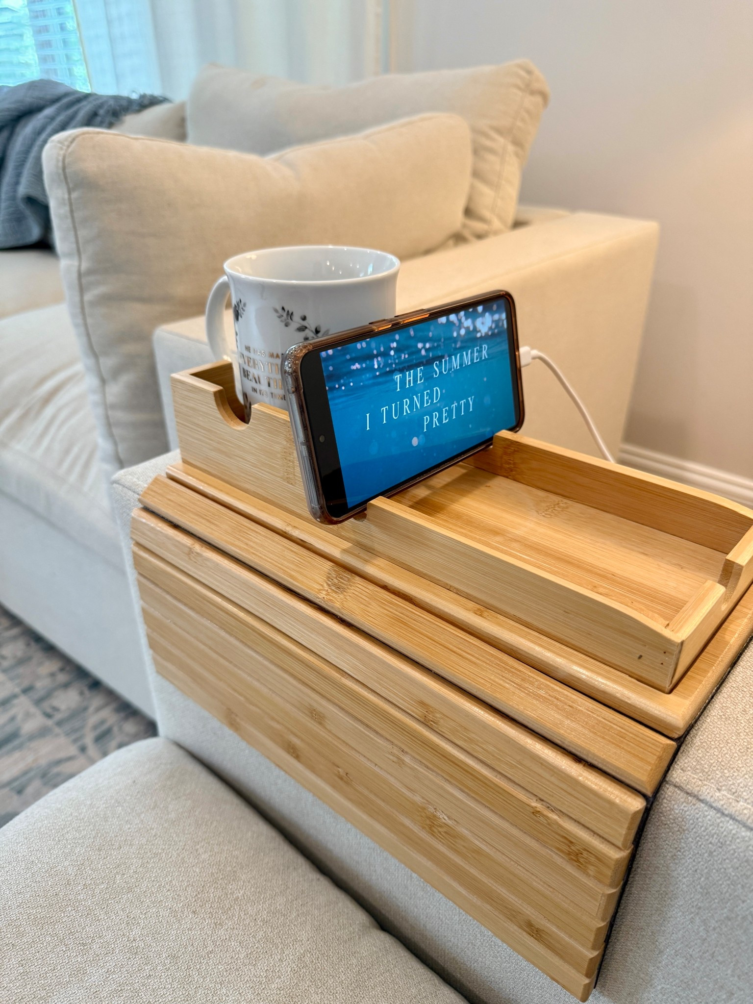 Getting real cozy while catching up on The Summer I Turned Pretty with a good cup of coffee 💙

This bamboo arm rest tray and cup holder is the perfect piece for these flat couch arms! It’s highly adjustable, has a soft felt backing so it’s grippy without damaging my fabric, and the cup holder and tray are removable and reversible. 🔄
For reference , this is the Cozey Couch in sandstone (sand something?). Very cozy and very easy to clean! Removable and machine washable covers, but I’ve wiped everything off with just water for months now! 🧽 

#LTKDecor #LTKFinds #HomeDecor #LivingRoom #TheSummerITurnedPretty #AmazonFinds 

#LTKFindsUnder50 #LTKSaleAlert #LTKHome