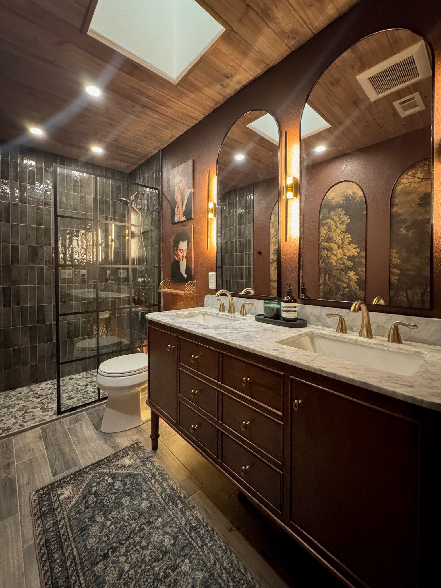 Bathroom Renovation Moody, dark rich tones, oak wood vanity, black shower tile, pebble rock shower tile, grid glass shower panel, arched mirrors, champagne bronze gold faucet and fixtures, wood plank ceiling, loloi rug

#LTKSaleAlert #LTKHome #LTKFamily