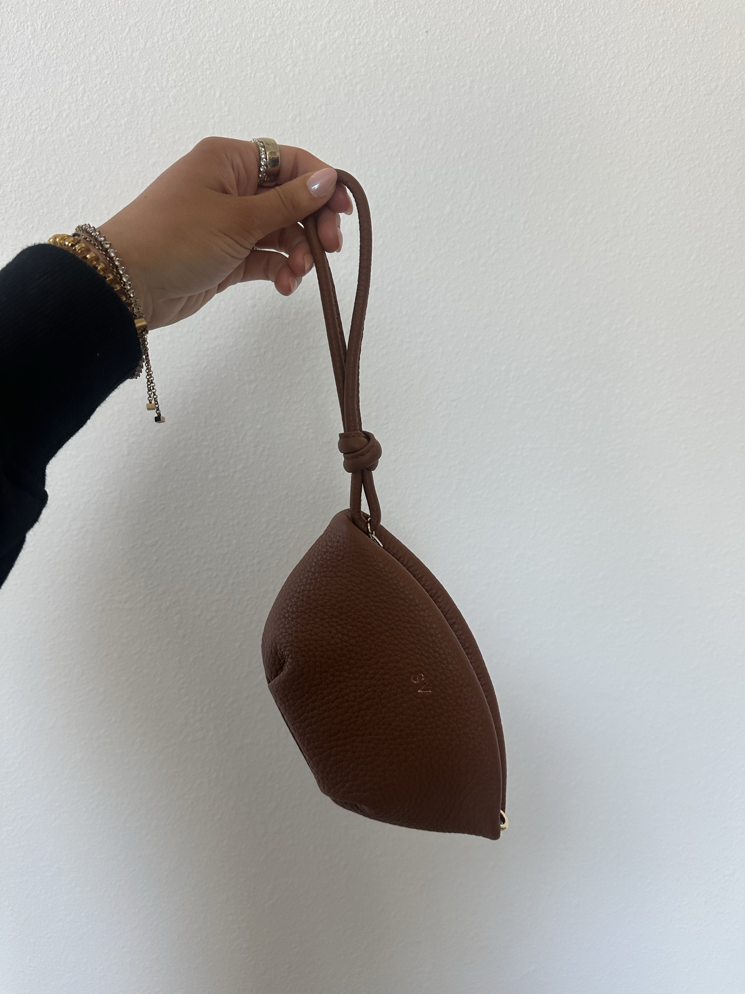 The Dumpling Clutch pairs its soft, curved silhouette with a knotted wrist strap and sleek zip closure making it a go-to for nights out or elevated day looks. Two exterior D-rings let you attach a strap for hands-free wear, while an interior zip pocket keeps small items tucked away. Finished with a smooth YKK metal zipper and lined in tan polyester, this piece is all style with just the right amount of structure. @Leatherology 

#LTKWedding #LTKgrwm #LTKootd