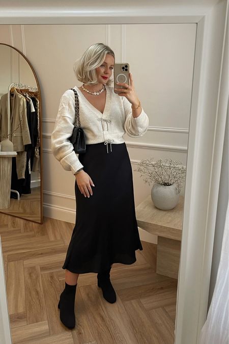 Cosy chic festive partywear outfit, perfect for Christmas cocktails with the girls. Cream knit cardigan with rhinestone bows from H&M, mango black satin midi skirt, black block heel sock boots & Pearl necklace from Astrid & miyu  

#LTKHoliday #LTKstyletip #LTKSeasonal