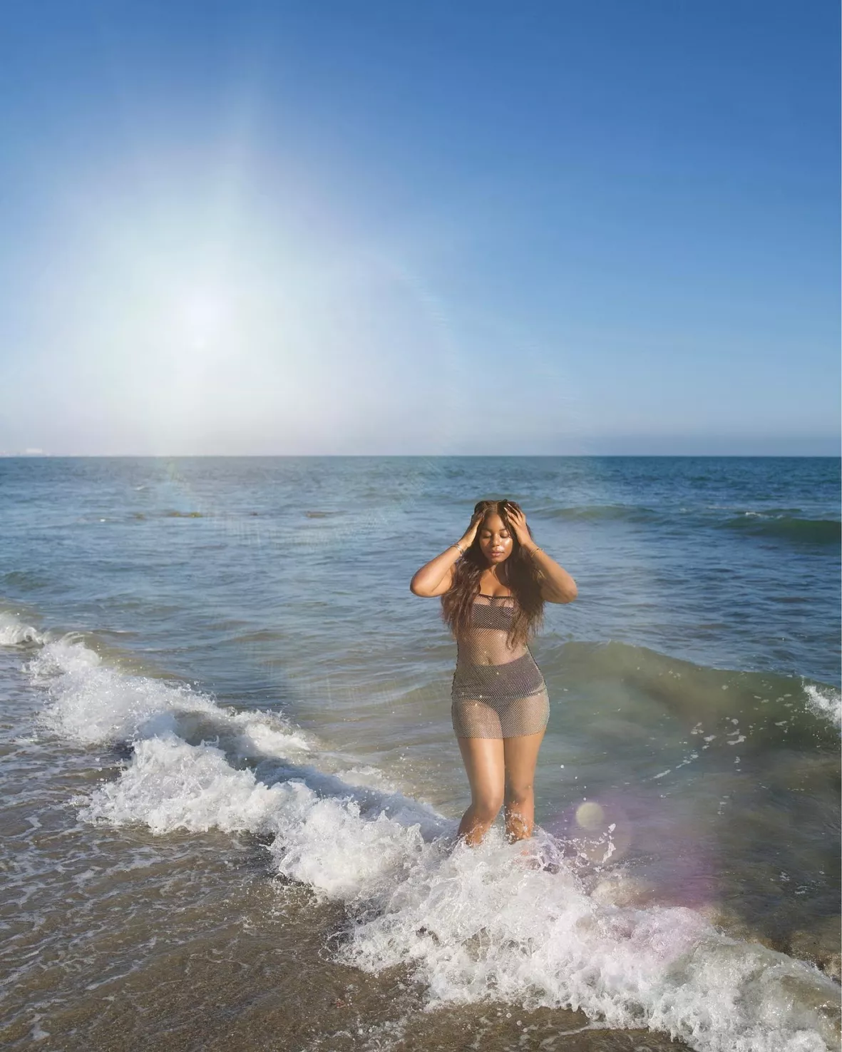 beautiful little girl in bathing suit and cap standing on beach. Stock  Photo