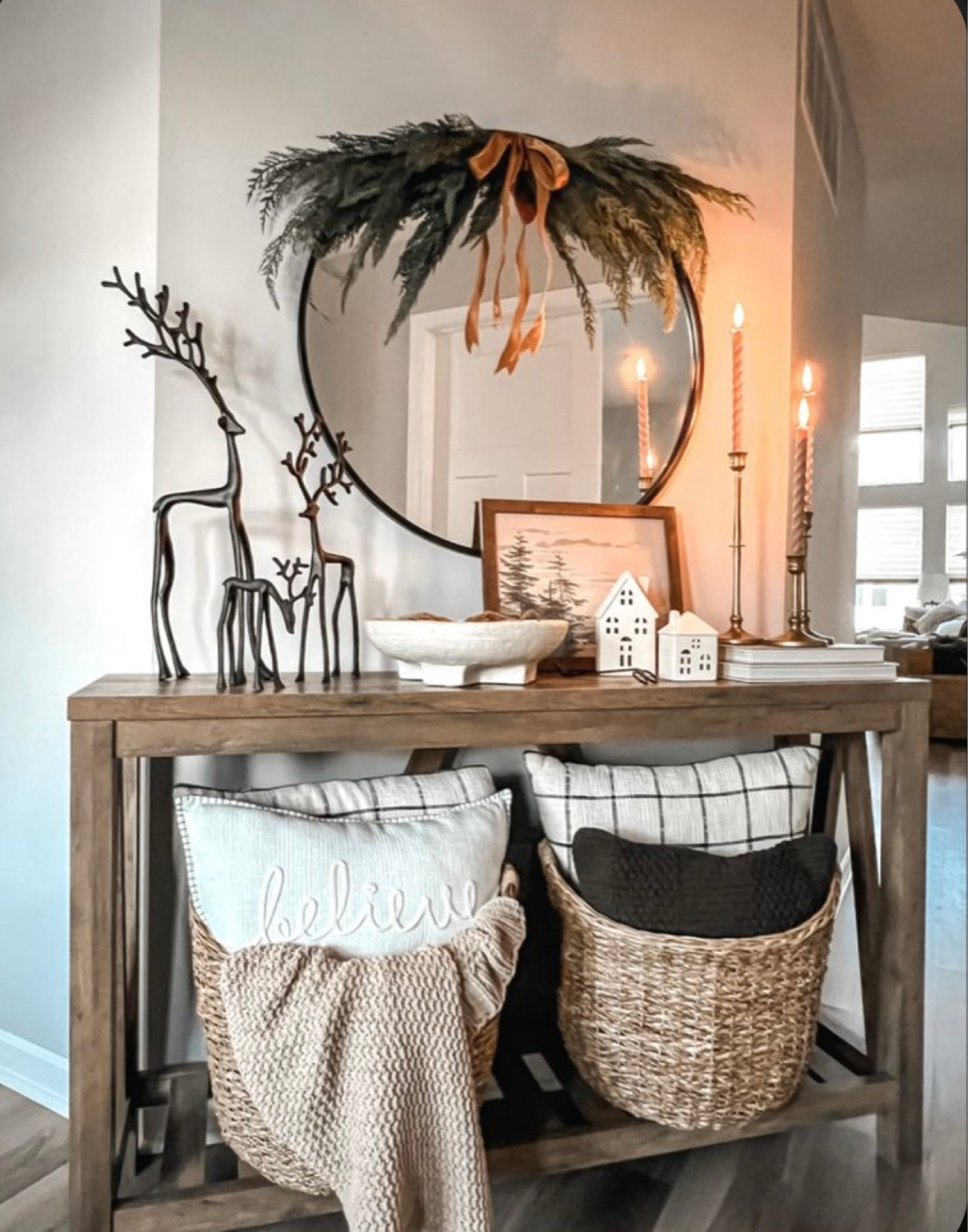 Christmas holiday console hallway table decor styling. 

Console hallway table. Wicker baskets. Holiday pillows. Tapered candles. Reindeer. Round mirror. Garland. Christmas decor. Holiday decor. Minimal decor. 