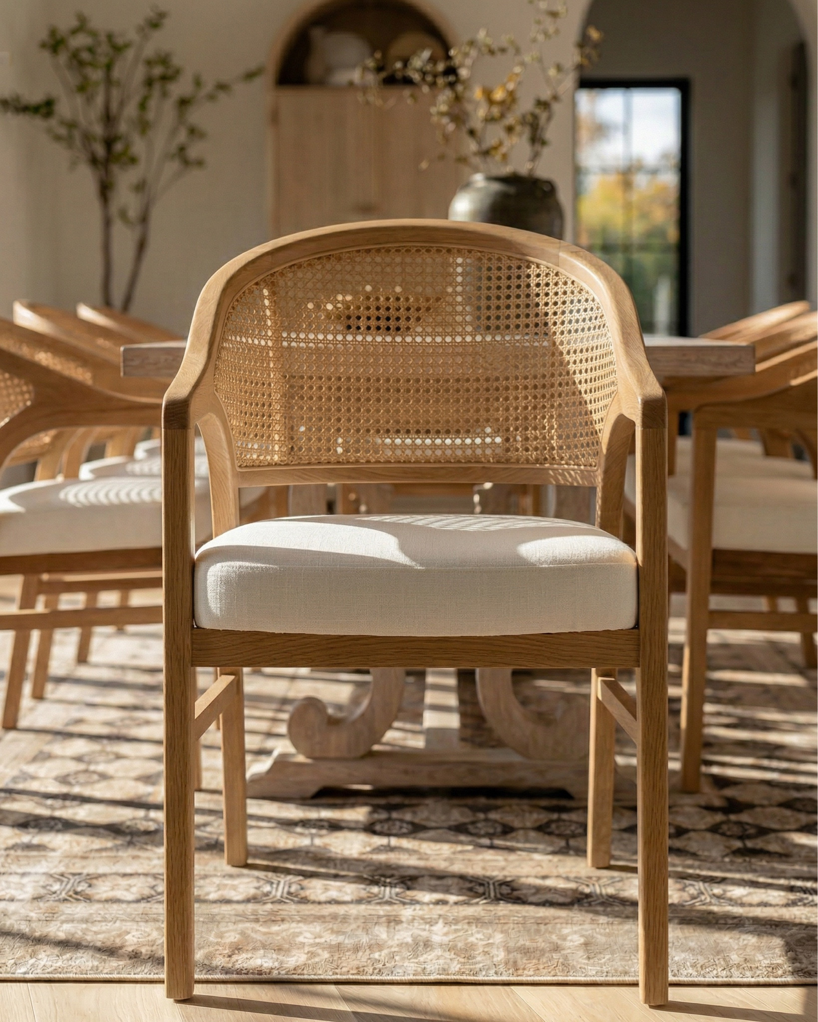 * Rectangular light wood dining table (traditional trestle base)
* Woven cane dining chairs (natural oak frame)
* Neutral vintage-style area rug (distressed pattern)
* Brass modern chandelier (linear / sculptural arms)
* Rustic exposed wood ceiling beams (reclaimed look)
* Large black-framed sliding glass doors (industrial style)
* Dark ceramic vase (handmade / organic texture)
* Dried floral arrangement (neutral stems)
* Sculptural brass decorative bowl
* Black ceramic candle holder (modern abstract form)
* White taper candle
* Small matte black decorative bowl
* Minimalist sculptural object (black accent piece)
* Light wood sideboard cabinet (fluted / ribbed detailing)
* Built-in arched niche cabinet (custom millwork look)
* Decorative pottery (neutral ceramic vases)
* Framed landscape wall art (classic / muted tones)
* Indoor olive tree (or faux olive tree)
* Neutral linen / textured textiles
* Warm light oak flooring
* Soft cream / off-white wall paint
* Arched doorway architectural detail


#LTKSaleAlert #LTKHome