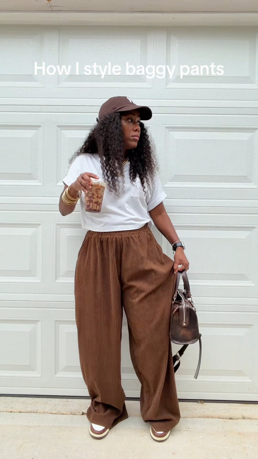How I style brown baggy corduroy wide leg high waisted pants with a white cropped pocket t shirt. I styled this casual outfit with a brown faux leather purse, brown NY baseball hat, and brown and white Nike Dunk low cacao wow sneakers.
