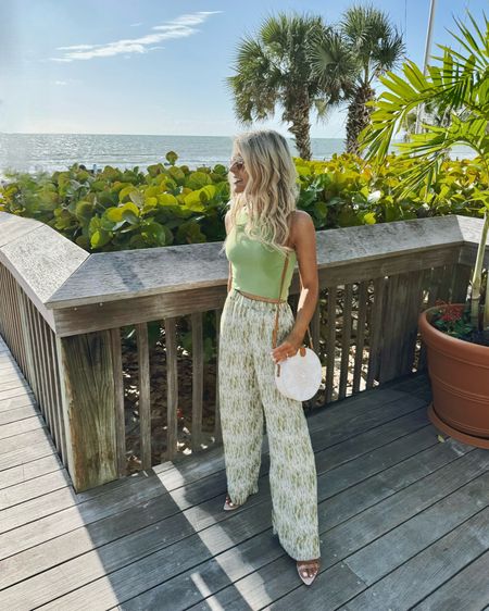 Vacation Outfit 🌴☀️ 

These wide leg pants are perfect for spring, summer, or vacation! I’m  wearing a size small in these high-waisted pants. They were the perfect length when I paired them with my favorite neutral heel. These pants also have a matching sleeveless blouse in the same print. 

I paired the springtime pants with my favorite Free People tank top. This tank top is a perfect closet staple for spring and summer. It’s a great basic for everyday layering. It comes in many colors. I wear a size XS/S for a cropped fit and a M/L for a full length fit. 

These clear heels are a must! They go everything and help instantly elevate a casual outfit. 

Vacation Outfits, Resort wear, Beach Outfits, Matching Sets, Spring Trends, Summer Outfits, Petite Fashion, Elevated Casual Outfits, Spring Outfits, Vici, Free People, Spring Pants, high waisted pants, high rise pants, plisse pants, pleated pants, green pants, lightweight pants, summer pants, tank top, green tank top, cropped tank top, spring basic, summer basic, crop top, vacation style, vacation outfit, resort wear, resort style, beach vacation, summer outfit, summer dress, matching set, spring fashion, spring style, casual outfit, spring trends, elevated casual, revolve, clear heels, neutral heels, nude heels, sandal heels, rattan bag, beach bag, straw bag, white bag, vacation purse, white crossbody 

#LTKstyletip #LTKtravel #LTKSeasonal