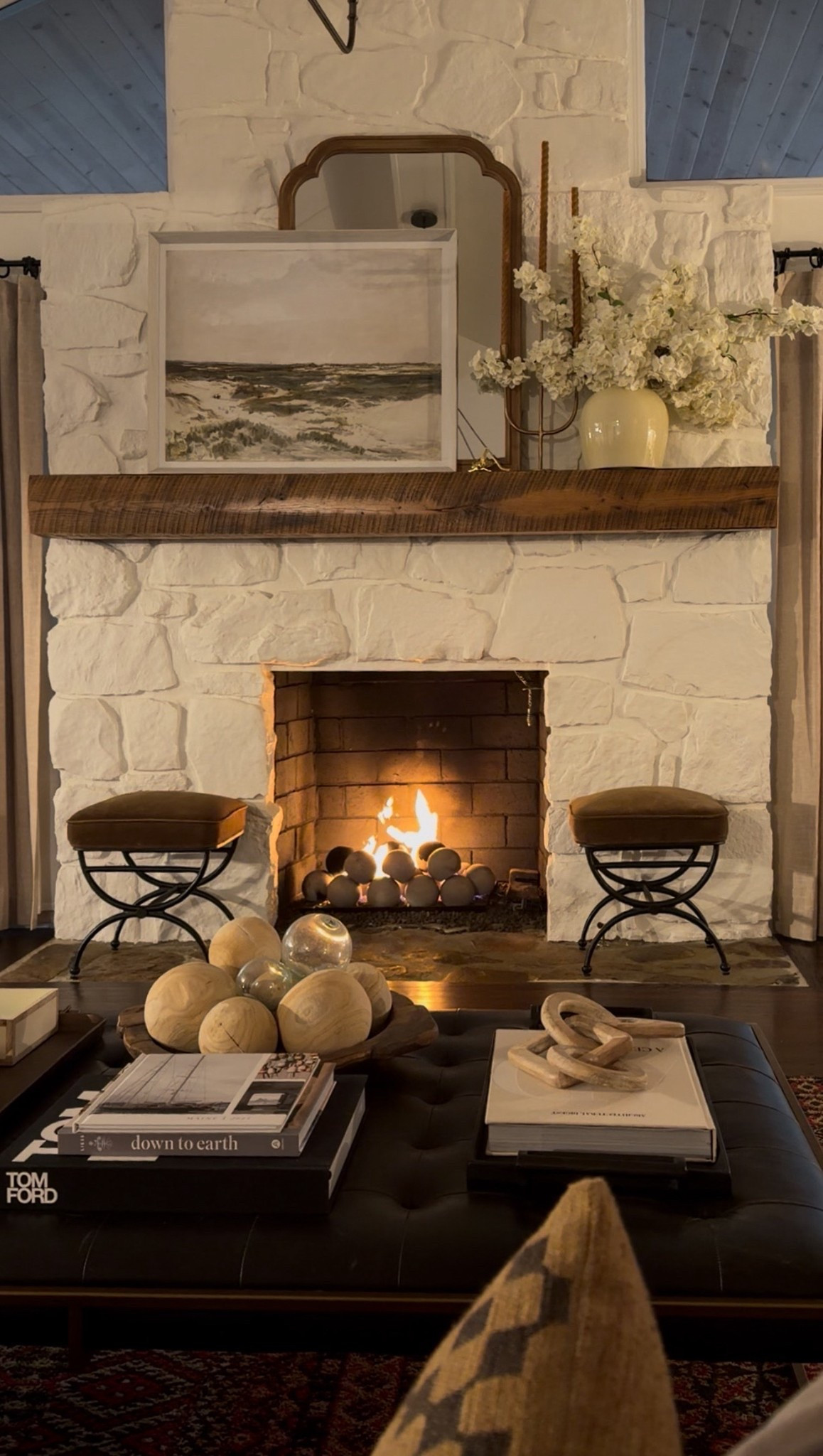 A cozy living room fireplace moment layered with texture and warmth 🤍
This space features a white stone fireplace, rustic wood mantel, fireplace hearth decor, and a glowing gas fireplace as the focal point. Styled with decorative wood spheres, coffee table books, a tufted leather ottoman, accent stools, neutral throw pillows, and ceramic vase florals for a collected, lived-in feel that’s timeless and inviting.

#eanesinteriors #livingroomdecor #fireplacedecor #stonefireplace #woodmantel #cozyinteriors #neutraldecor #rusticlivingroom #classicinteriors #homeinspo #ltkhome #interiordesign

#LTKSeasonal #LTKdayinmylife #LTKHome