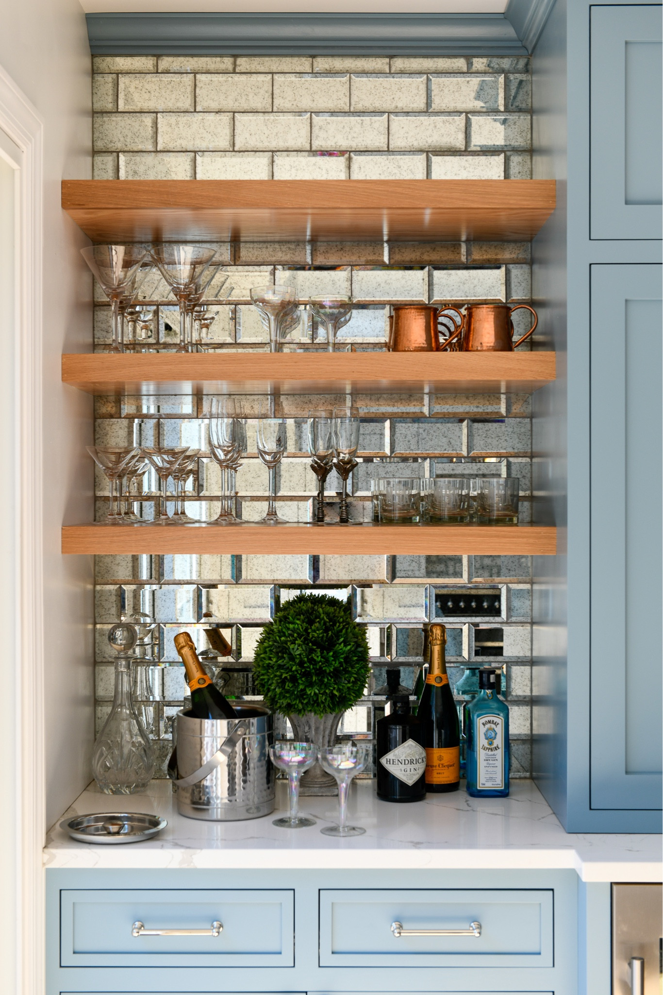 A glamorous bar with mirror tile backsplash, floating shelves, champagne, glassware, copper mugs

#LTKFind #LTKhome
