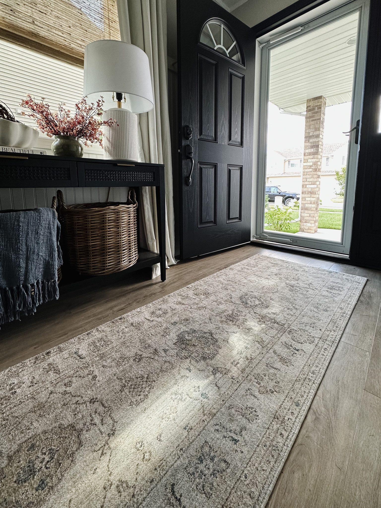 Entryway design, entryway decor, Joanna Gaines with Magnolia x Loloi rugs in sky/gold, woven baskets, black console table, black front door, pink florals, blue throw blanket, scalloped ceramic bowl, white ceramic lamp, wooden woven blinds, pottery barn dupe curtains 

#LTKFind #LTKstyletip #LTKhome