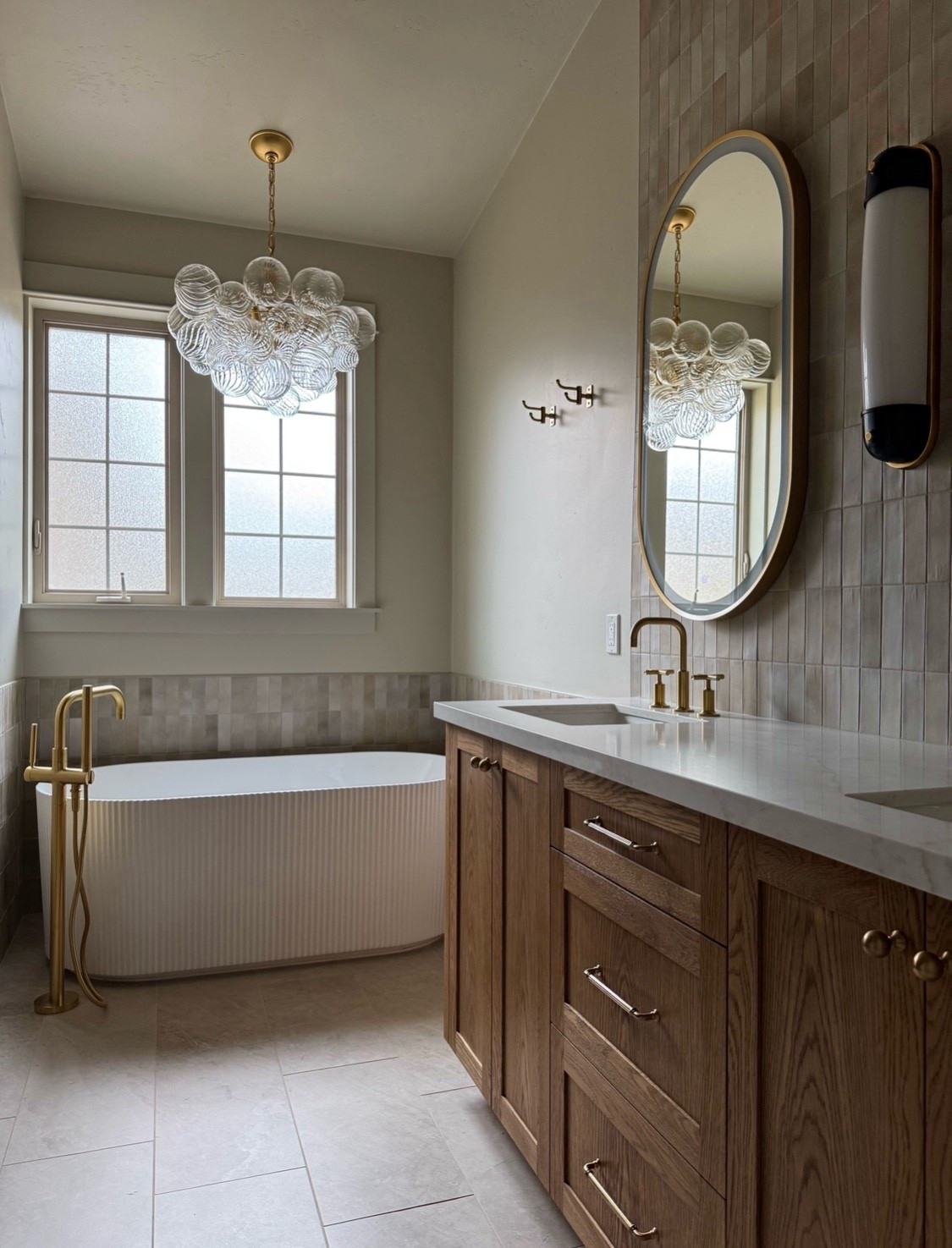 Widgi creek retreat primary bathroom remodel: material details.
Reeded cabinet pulls
Fluted free standing bathtub 
Oval mirror 
Bathroom light fixtures
Floor mount tub filler 
Adjustable towel hooks 
Neutral bathroom tile 

#LTKSaleAlert #LTKStyleTip #LTKHome