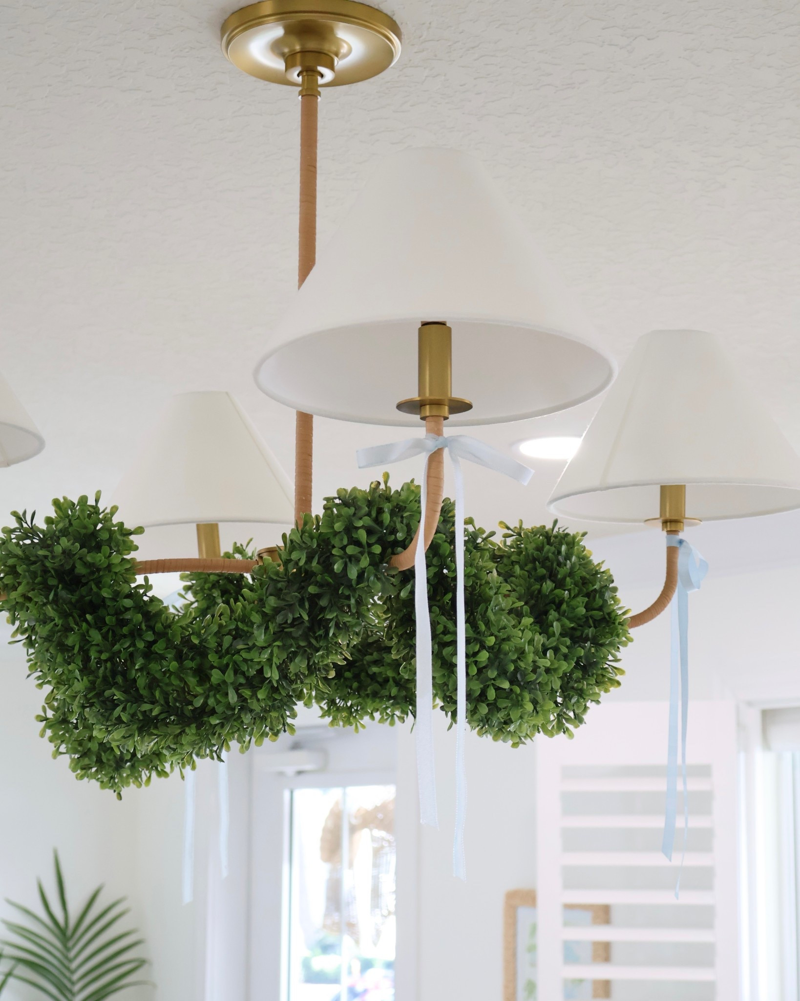 This 4-light chandelier from Wayfair gives total coastal-chic vibes with warm brass + rattan details and crisp white shades. Such an easy upgrade for your living room, dining room or bedroom light fixture. I added faux boxwood garland and light blue ribbon to decorate for the holidays ✨💚🩵

#LTKHome #LTKSeasonal #LTKSaleAlert