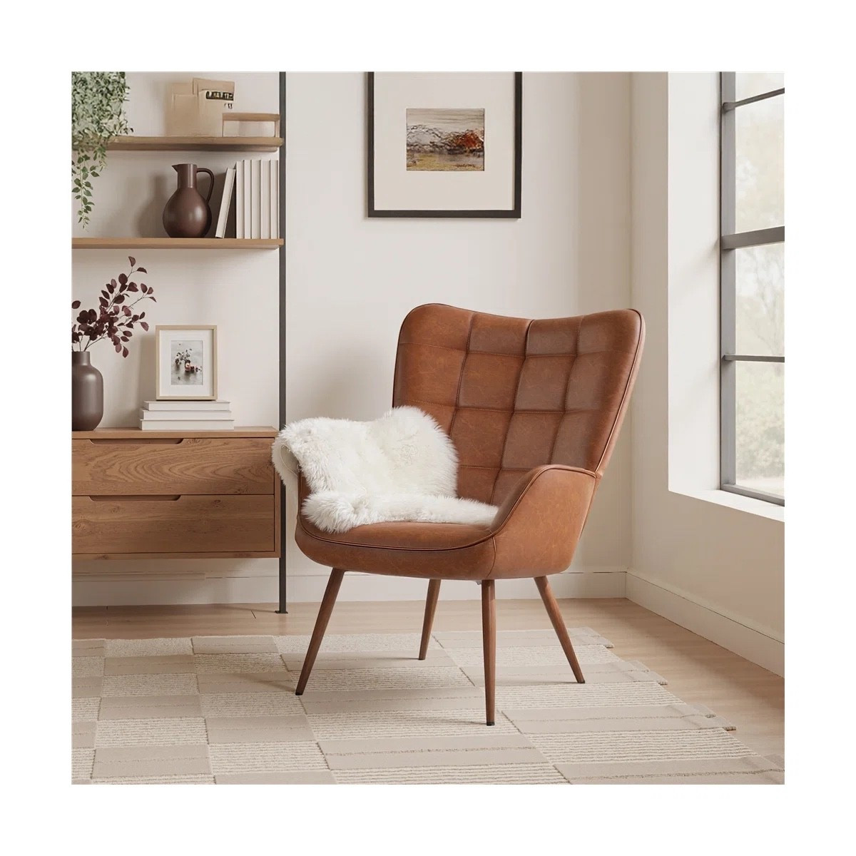 This faux leather wingback accent chair from Wayfair is the perfect statement piece for a cozy reading corner or living room refresh. The warm cognac brown upholstery, sculpted wingback silhouette, and tapered wood legs bring a timeless mid-century feel to any space. Styled with a plush faux fur throw, neutral area rug, wood console cabinet, floating shelves, framed wall art, and decorative vases for an effortlessly layered look. A versatile accent chair that works beautifully in modern, rustic, and transitional homes.