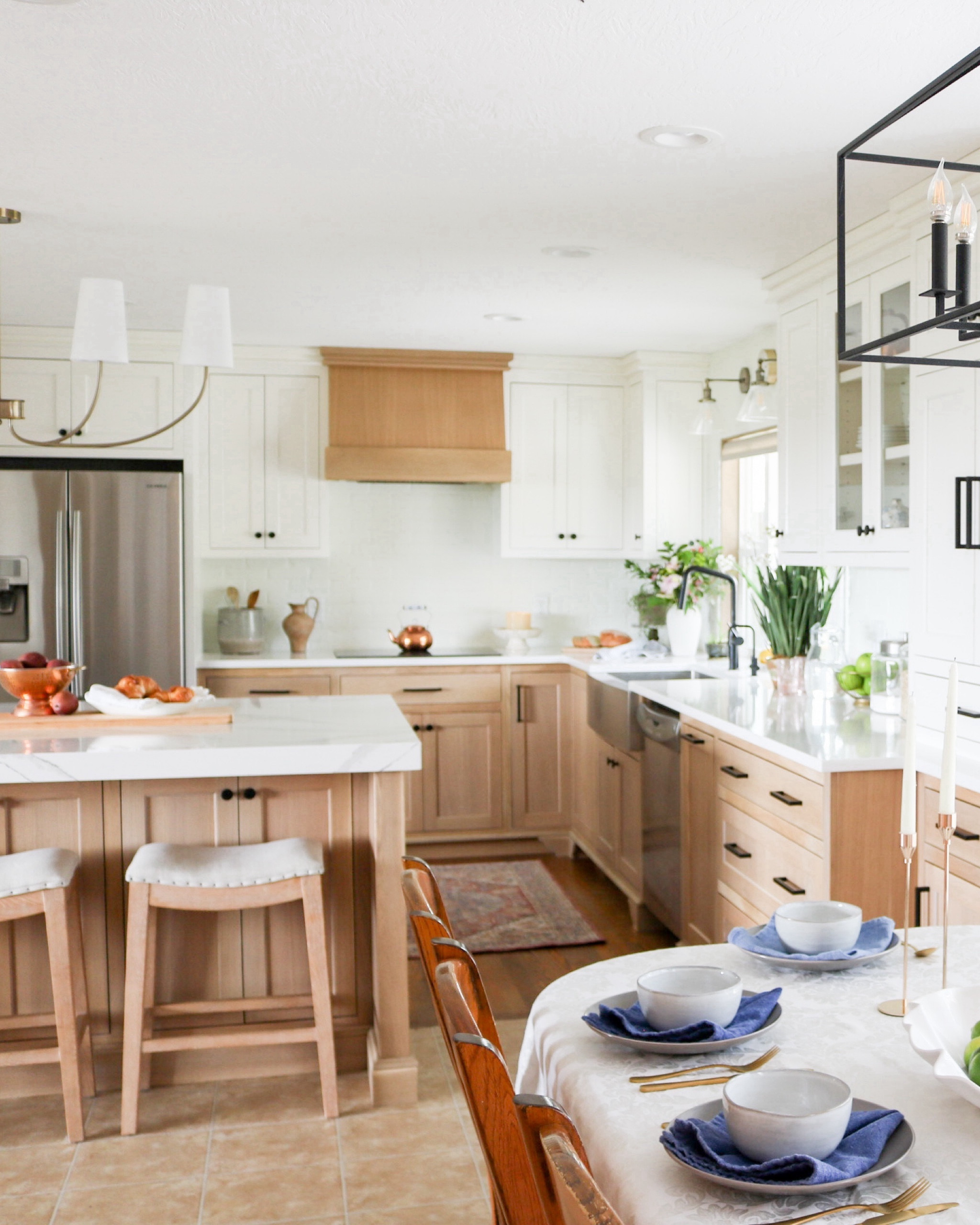 Modern French Country kitchen with candelabra shade chandelier, white oak cabinets, black cabinet pulls and knobs, matte black kitchen faucet, upholstered counter stools and black cage lantern dining room light  

#LTKsalealert #LTKhome
