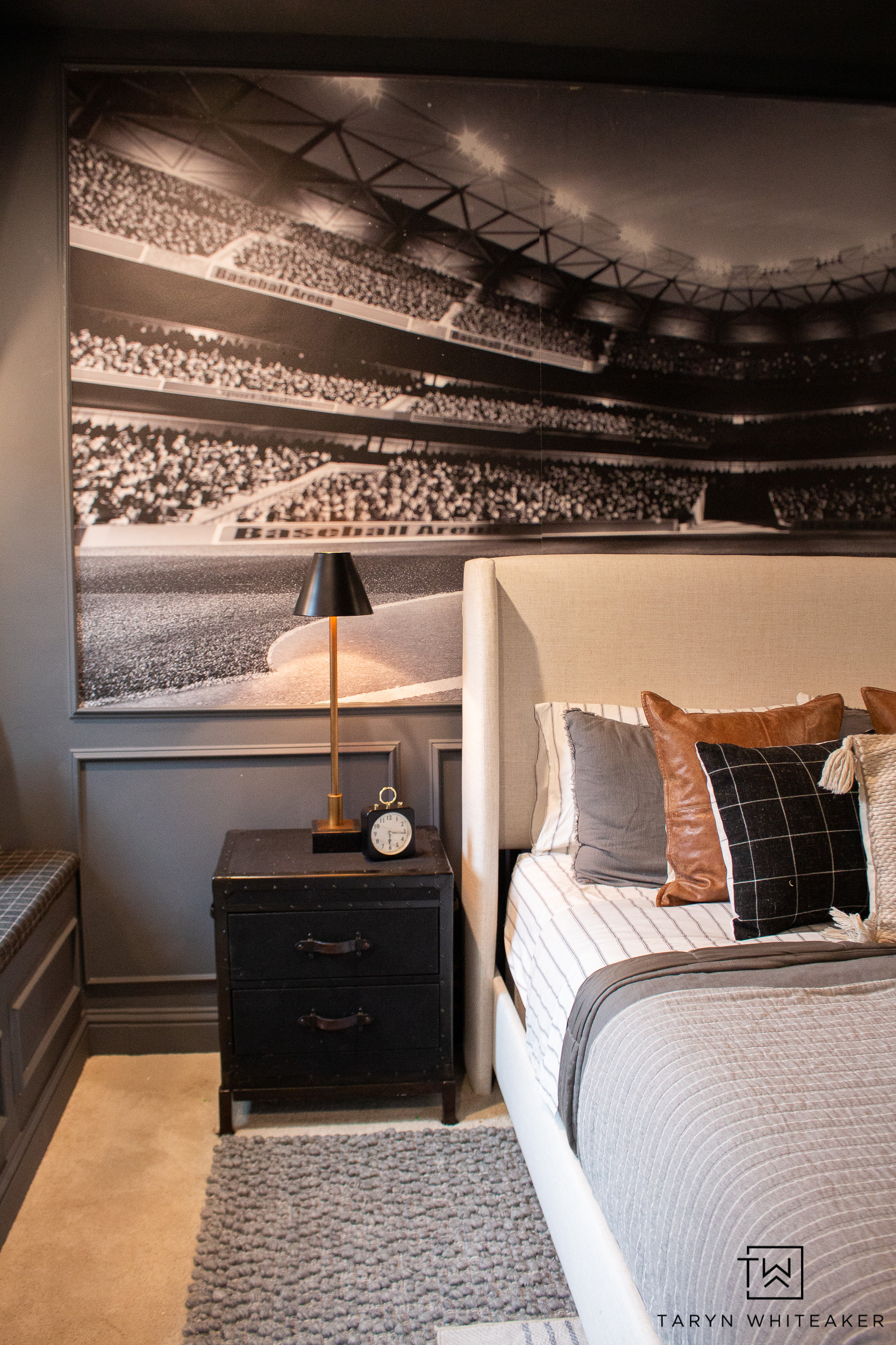 This sports-themed bedroom feels sophisticated and modern with its dark paneling, oversized stadium mural, and layered neutral bedding. The mix of leather, plaid, and textured pillows adds warmth and dimension, while the black nightstand and brass lamp tie the whole look together. It strikes the perfect balance between a grown-up space and a fun, personal room.
Linking the bedding, pillows, rug, lighting, and similar decor pieces to help you recreate this elevated sports bedroom design.

#LTKHome #LTKSeasonal #LTKKids