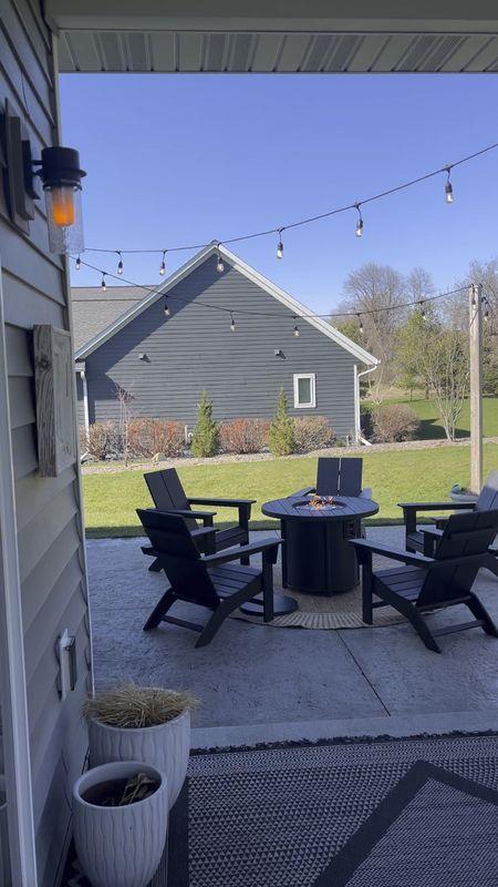 Outdoor living with black Polywood Adirondack chairs and fire table. Outdoor rug. String lights. Patio furniture. Target outdoor finds. 

#LTKhome #LTKSeasonal
