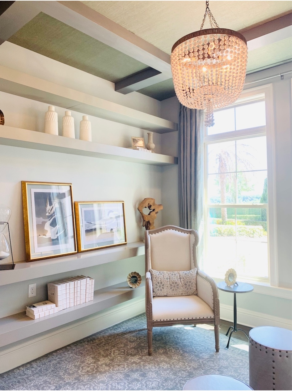 Sage green accent wall with shelves, decor, grass wall paper on ceiling, rug, chandelier, accent chair and side table. 

#LTKSpringSale #LTKhome #LTKstyletip