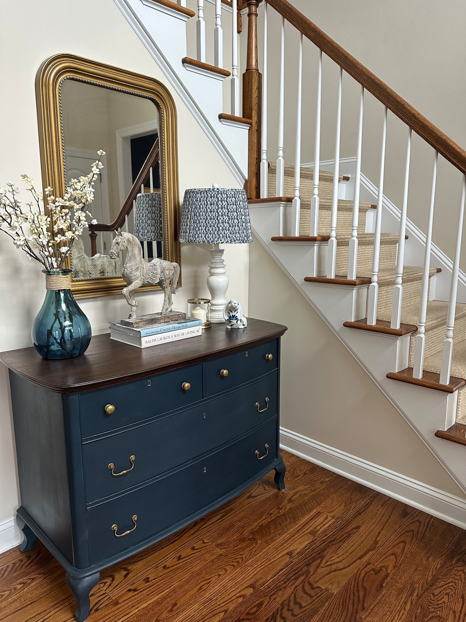 Classic foyer decor with navy blue dresser, gold mirror and lamp with pleated lampshade.

#LTKHome #LTKSeasonal