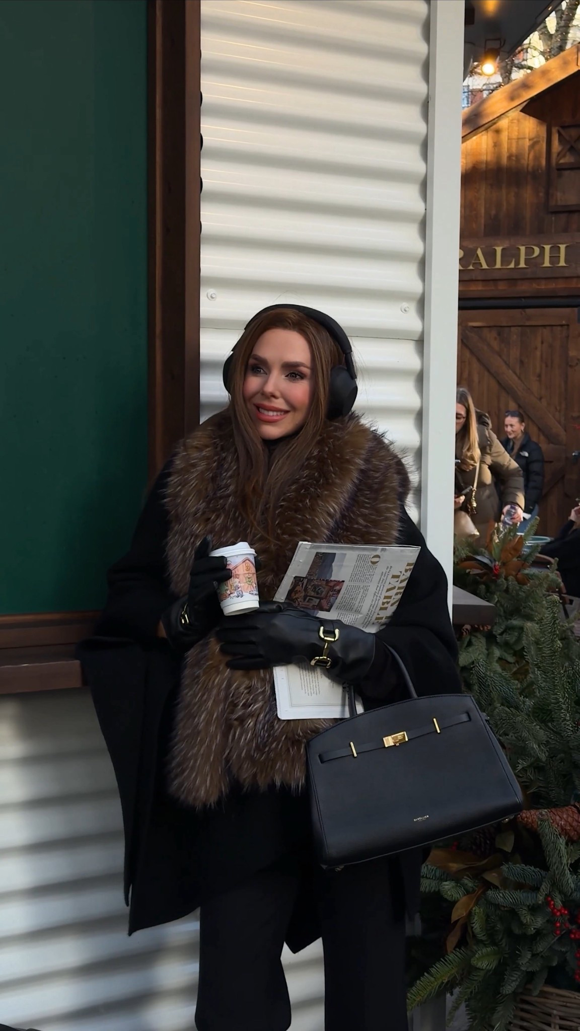 A black wool knit cape with a fur trim hood styled with a coordinating fur scarf, paired with black tailored trousers and black sock boots with a stiletto heel for a sleek winter silhouette. Finished with the small black Demellier Hudson bag, a timeless, structured everyday handbag that elevates cold weather outfits, alongside the Katie Loxton travel bag for practical yet polished styling. A chic, luxury-inspired winter look ideal for city wear, travel days and refined everyday dressing.

#LTKwinter #LTKuk #LTKfestive