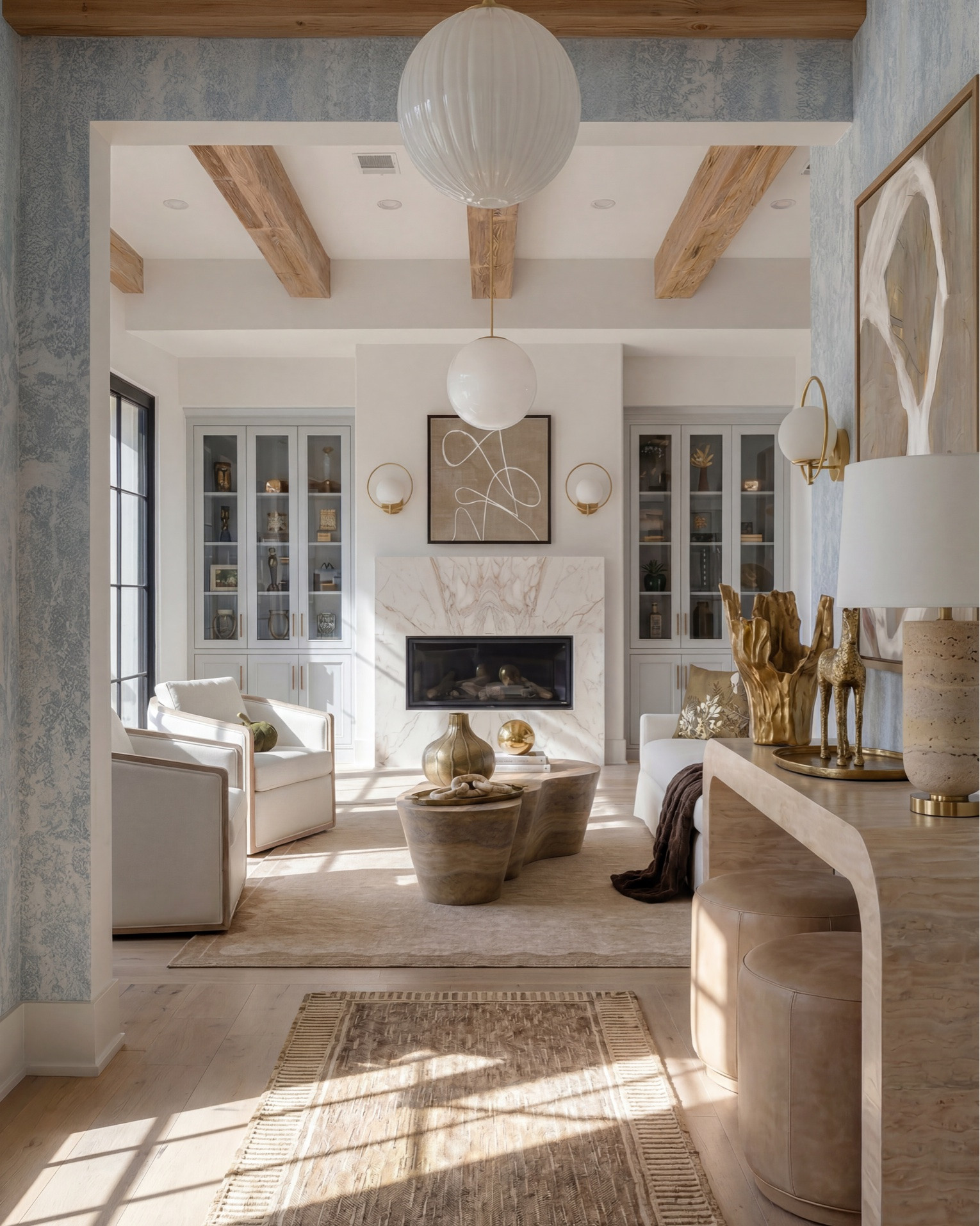 Shop the look:
* White upholstered accent chairs (modern box frame)
* Curved white sofa / loveseat
* Sculptural wood coffee table
* Organic wood side table stools
* Neutral textured area rug
* Marble fireplace surround (warm veining)
* Built-in glass display cabinets
* Light wood console table
* Upholstered round ottomans / stools
* Natural wood ceiling beams
* Light oak hardwood flooring
* Large white globe pendant light
* Fluted white glass pendant chandelier
* Brass wall sconces with globe shades
* Neutral ceramic table lamp
* Modern brass accent lighting
* Abstract neutral wall art
* Oversized framed artwork
* Gold sculptural decor objects
* Decorative brass tray
* Textured ceramic vase
* Organic sculptural vase centerpiece
* Decorative books for styling
* Neutral throw blanket
* Patterned accent pillow
* Small tabletop sculpture accents
* Textured runner rug
* Minimalist console styling
* Soft blue textured wallpaper
* Black framed windows
* Modern built-in shelving decor
* Layered neutral textiles

#LTKsale #LTKhome