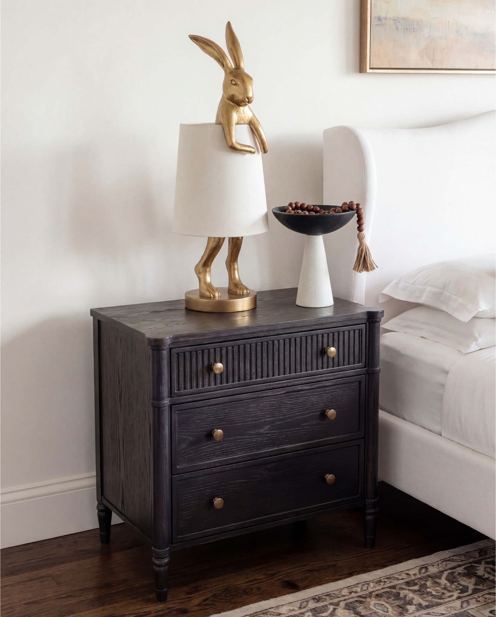 Shop the Look: Bedroom Refresh
• Upholstered wingback bed (ivory fabric)
• White cotton bedding set
• Neutral euro pillows
• Black and tan patterned accent pillows
• Chunky knit throw blanket (camel brown)
• Dark black wood nightstands
• Decorative bunny Brass table lamps with white shades
• Framed abstract wall art (neutral tones)
• Vintage-style area rug (beige and taupe)
• Dark black wood dresser with brass hardware
• Brass ring drawer pulls
• Glass hurricane candle holders
• White pillar candles
• Decorative brass tray
• Sculptural brass decor object
• Small stone sculpture 
• Light beige linen curtains
• Ceramic vase (off-white)
• Decorative branches
• Coffee table books (neutral covers)
• Upholstered bench at foot of bed (cream fabric)
•upholstered wood accent chair 
•round ribbed black end table 

#LTKSaleAlert #LTKHome