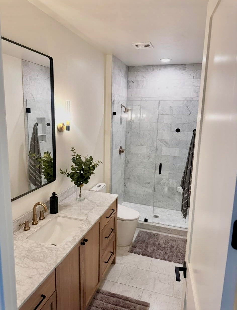 I wanted this bathroom to feel clean, warm, and timeless, so I layered soft wood tones with marble finishes, warm brass fixtures, and simple black accents. The little details really make the space feel finished without feeling overdone.

I’ve linked the bathroom mirror, vanity lighting, rugs, hardware, and decor pieces that helped bring this look together. These are the kinds of everyday pieces I continue to use because they feel elevated and functional at the same time. 
@Wayfair 
@Target 
@Walmart 

 #LTKU #LTKHome #LTKSaleAlert