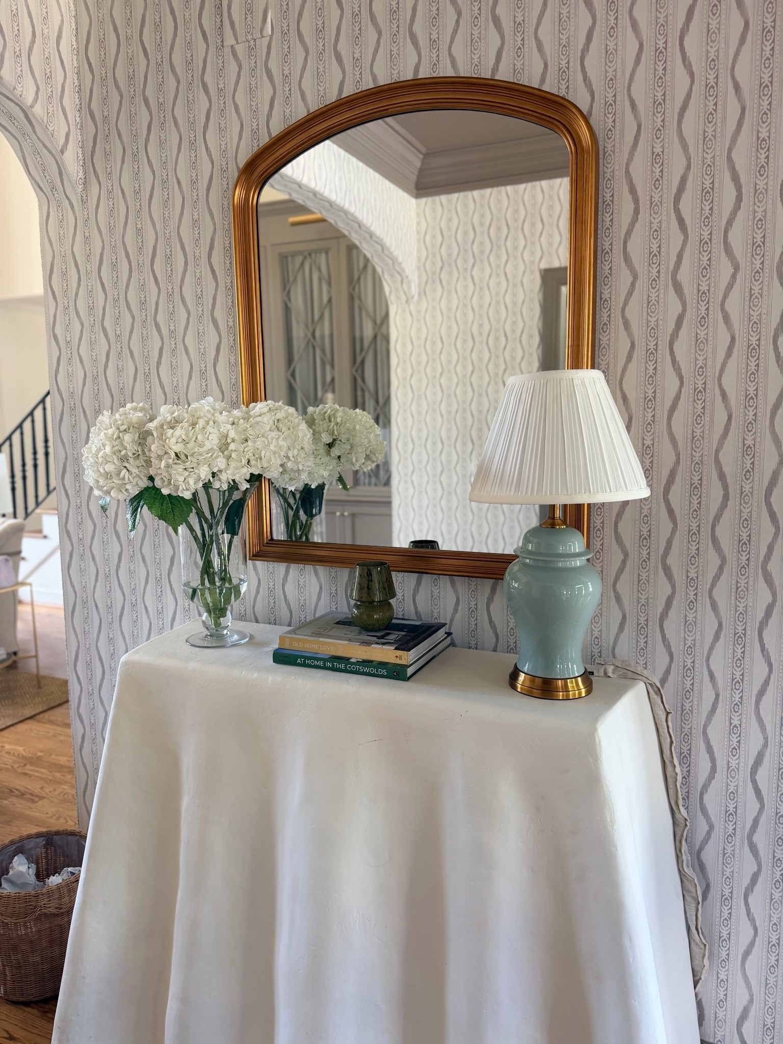 Entryway styling! Love this gorgeous target vase $35 👏🏽 and these faux (feel so REAL) hydrangeas. I used 2 packs of three to fill this vase. Wavy console is old Ballard but linked my wavy ikat wallpaper, mirror and lamp. Everything linked but console table for you!

Paint color of entry trim and ceiling is Charleston Gray by Farrow & Ball which is also the paint color used on the adjacent built ins!