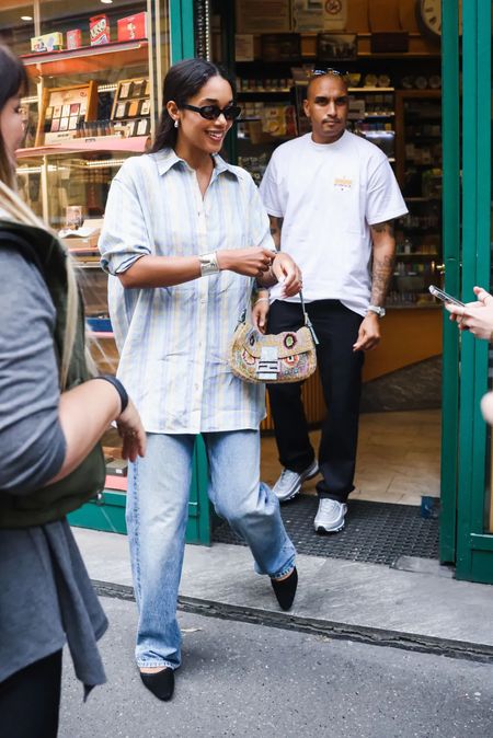 Shop Laura Harrier's loose stripe button front shirt, baggy jeans, vintage designer bag and a pair of almond shape black mule oval shape sunglasses silver cuff #LauraHarrier #CelebrityStyle

#LTKStyleTip