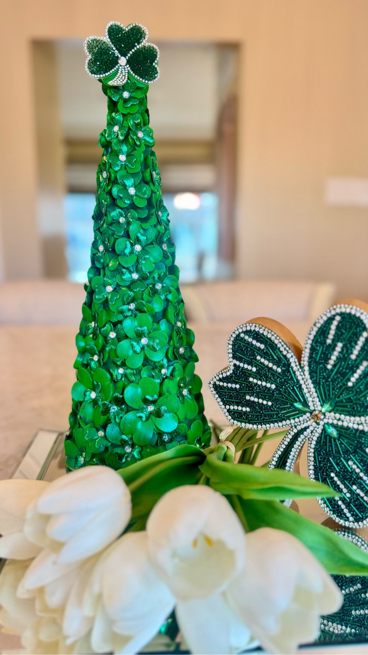 A little St. Patrick’s sparkle for your home décor 💚✨ This glam shamrock cone tree is covered in layered emerald florals and rhinestone accents for the perfect festive touch. Styled on a mirrored tray with white tulips and a jeweled shamrock accent for an elegant pop of green. Simple pieces + a little sparkle = instant seasonal magic!

#ltkhome #ltkseasonal #ltkdecor #stpatricksdaydecor #shamrockdecor #greenhomedecor #holidaydecorideas #glamdecor #springdecor #seasonaldecor
