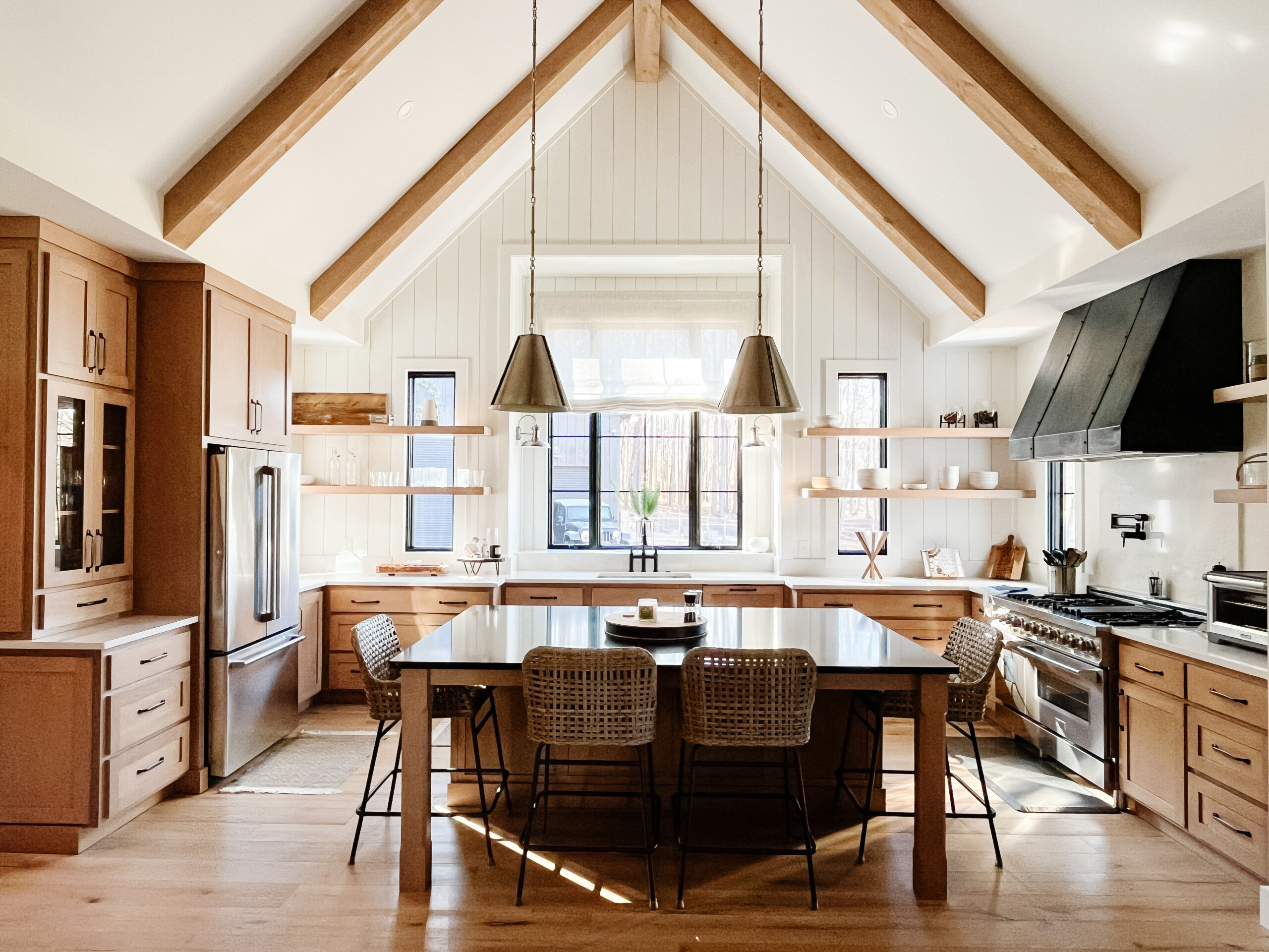 ✨ This kitchen has all the elements we love — vaulted ceilings, exposed beams, and layers of warm natural wood. The custom details, from the metal vent hood to the gold-accented pendants and woven barstools, bring texture and personality to the space. With sunlight streaming in and a spacious island made for gathering, it’s the perfect mix of form and function. ☀️🍽️ Shop the look and bring this bright, inviting style into your own home.
#KitchenDesign #LTKHome #ModernFarmhouse 

 