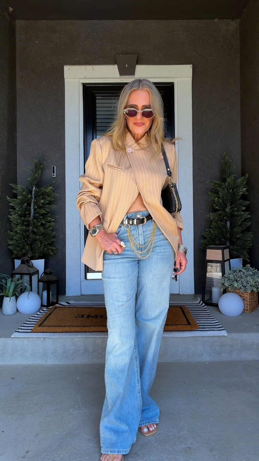 Fall date night outfit with blue jeans, an asymmetrical tan striped blazer, sandals, and a black belt with gold chain detail. The Louis Vuitton Pochette Liv and statement sunglasses give a simple jeans-and-blazer outfit that polished, elevated feel that works perfectly for dinner or drinks without feeling overdressed. 

 #LTKootd #LTKSeasonal #LTKOver40