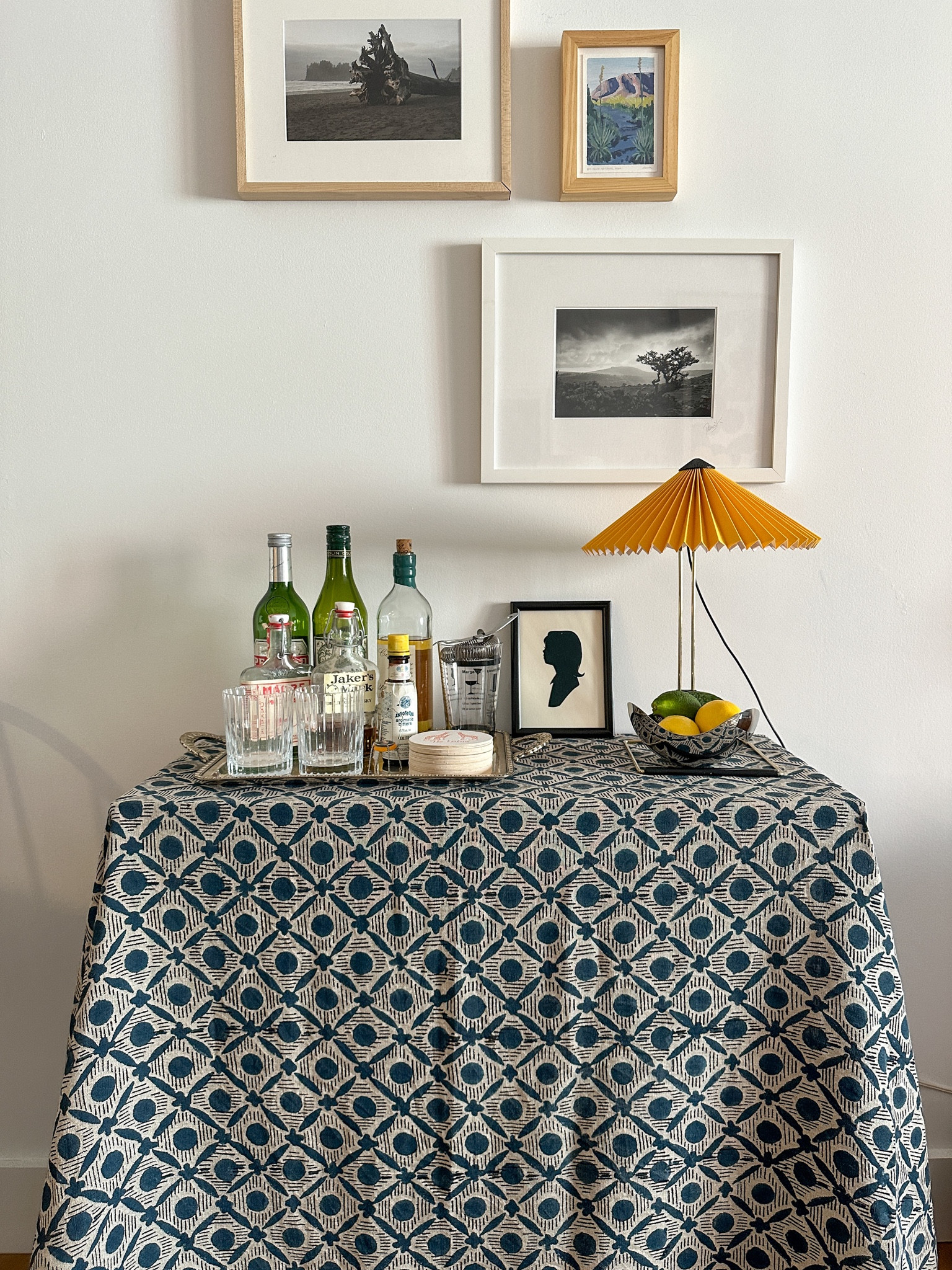 When I designed my home bar, I wanted it to have lots of storage and make an aesthetic statement. And I think it did just that. See below to shop my bar!

Bar carts are cool, but my bar is made up of a shelf with a tablecloth on top for a boho look that conceals bottles and glassware underneath. I included the exact shelf off Amazon and a similar looking blue tablecloth. 

Then it all comes down to accessories. The table top currently holds a tray with glasses, bottles and coasters; a lamp; and bowl for citrus. Everything you need to whip up and serve a drink on the fly. 

#LTKhome