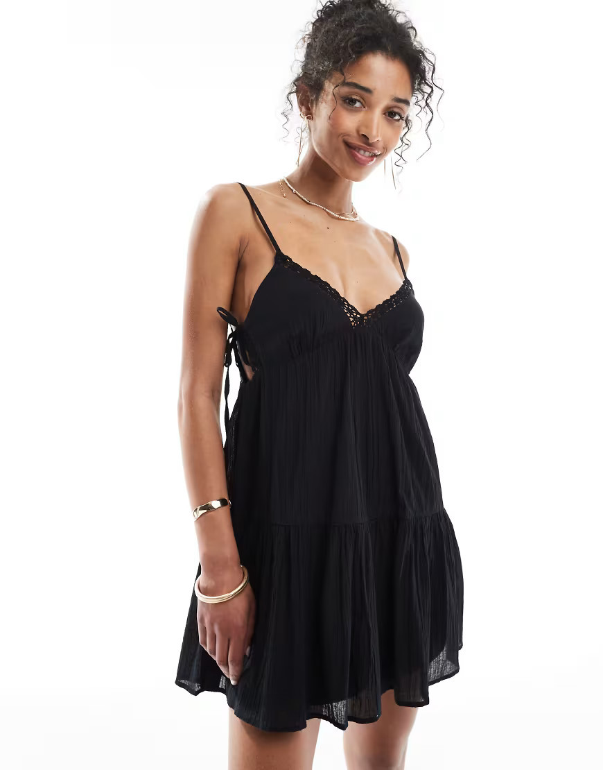 Bershka – Gestuftes Minikleid in Schwarz mit schmalen Trägern und Spitzenbesatz | ASOS (Global)
