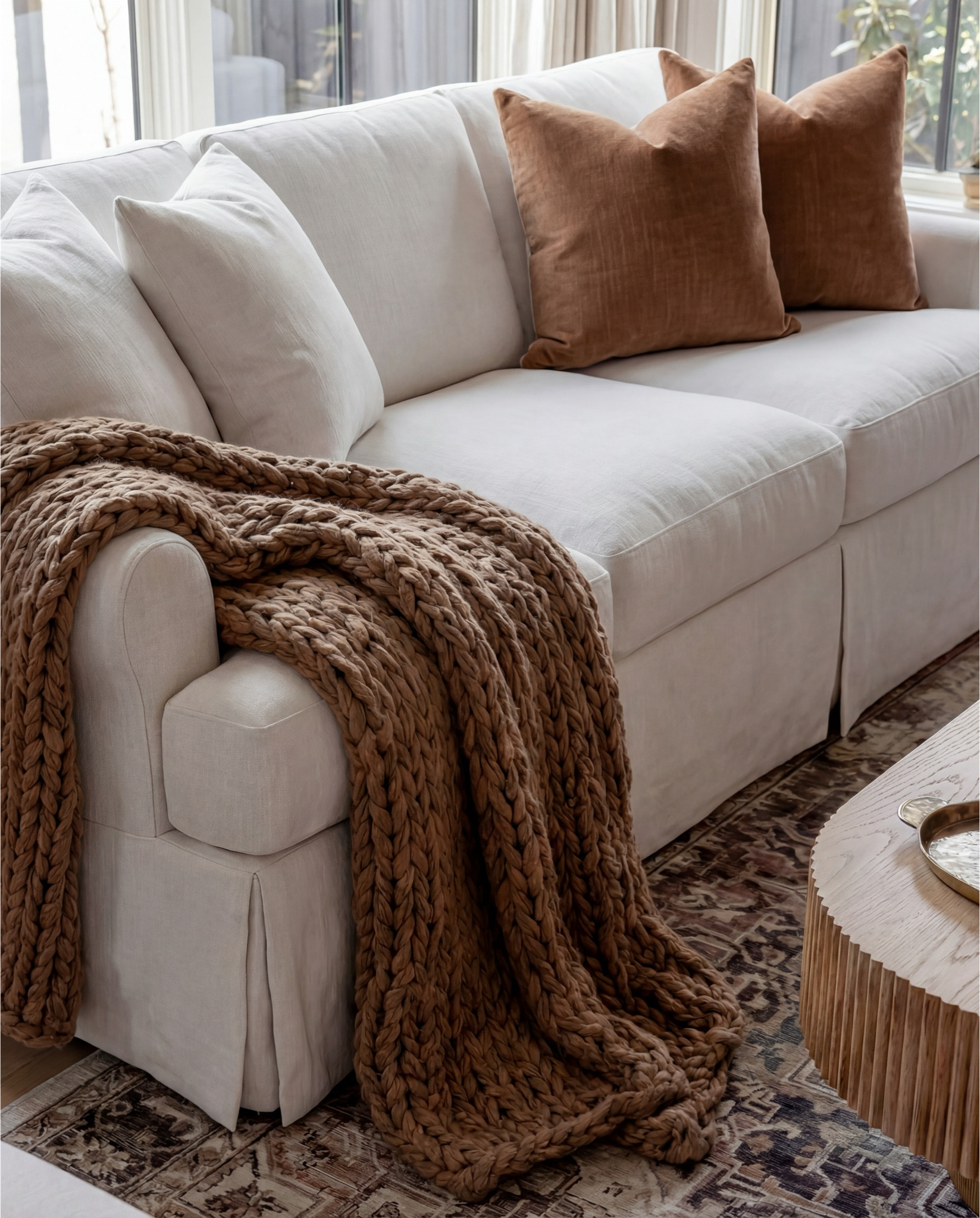 Shop the Look:
• White upholstered sofa (clean-lined, low profile)
• White upholstered armchairs (pair)
• Light wood round coffee table (fluted or ribbed base)
• Neutral vintage-style area rug (muted brown and beige tones)
• Marble fireplace surround
• Black fireplace insert
• Large framed landscape wall art (soft blue and neutral tones)
• Brass wall sconces (pair, globe style)
• White globe pendant light with brass detail
• Natural wood ceiling beams
• Light wood flooring

Coffee Table Styling:
• Large white ceramic vase (rustic sculptural style)
• Decorative hardcover books (neutral covers)
• Gold abstract heart sculpture
• Brass oval tray
• Decorative brass object (sculptural accent)

Sofa Styling:
• Neutral throw pillows (warm beige)
• Chunky knit throw blanket (camel or warm brown)

Media Console Area:
• Light wood sideboard / media console (carved front detail)
• Brass cabinet knobs
• Black figurine sculptures (musician figures, set of three)
• Brown ceramic vase
• Dried branches / minimalist floral stems
• Brass decorative tray

#LTKHome #LTKSaleAlert #LTKFindsUnder100