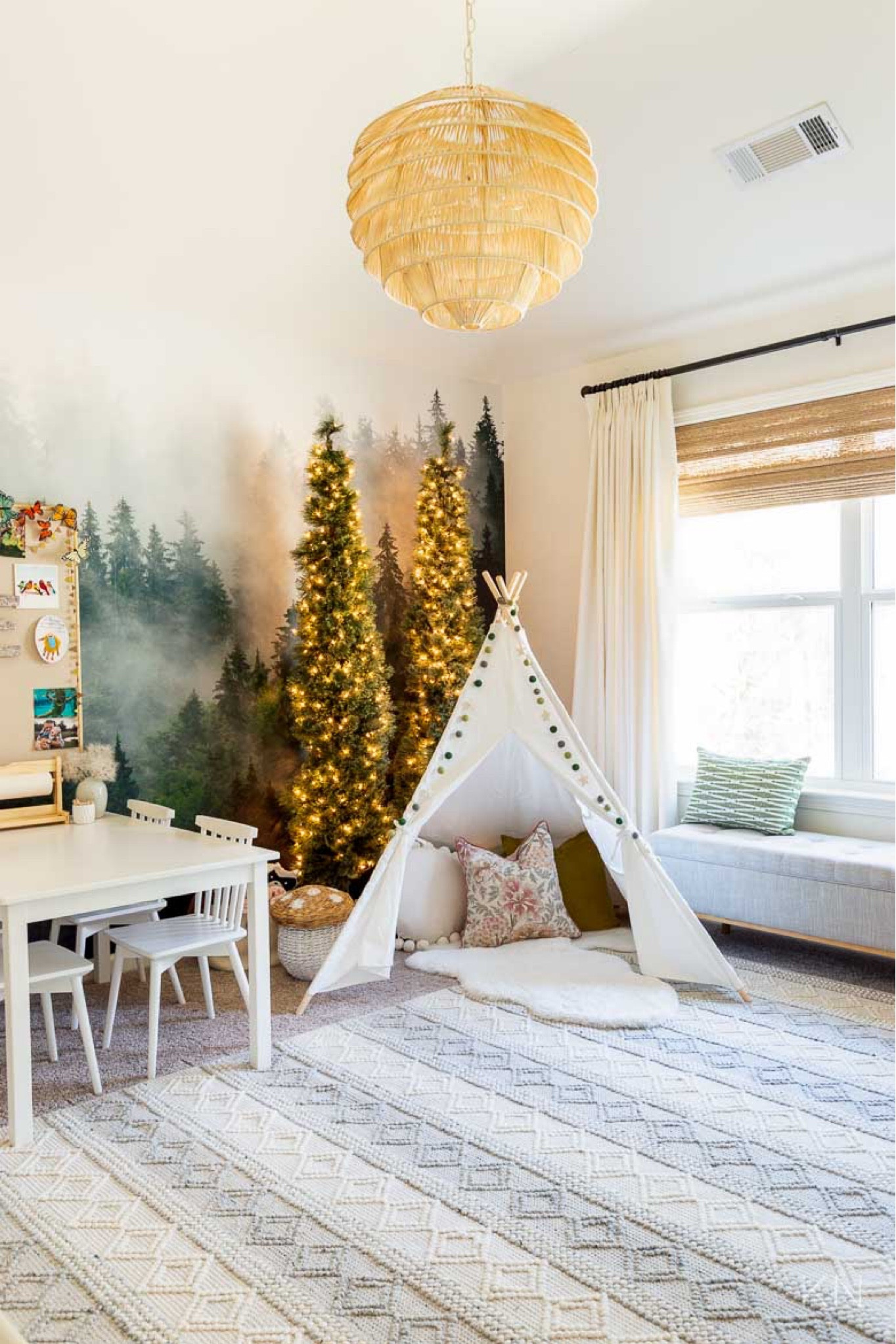 This kid friendly playroom features forest mural wallpaper, slim pre-lit trees and a teepee tent. It also includes strategic storage in this padded storage bench and natural storage baskets. home decor playroom decor kid room play table play chairs natural rug

#LTKstyletip #LTKkids #LTKhome