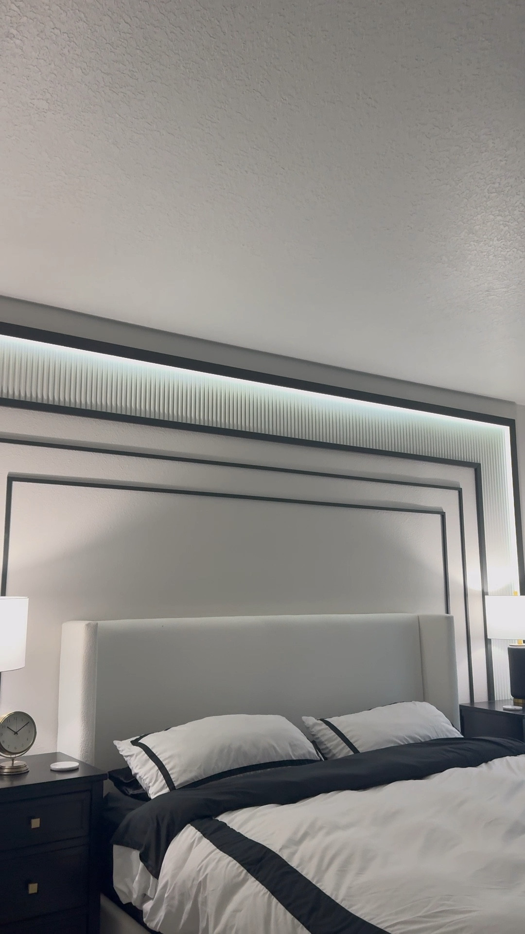 Our main bedroom feels like a boutique Hotel suite
I wanted something timeless with a little edge — and this custom headboard wall was the perfect solution.

We framed the wall in molding to create a structured backdrop and feel like s giant headboard. The upholstered headboard I picked to be grand but also disappear into the wall so the main focus was the overall look. The sleek black trim makes it feel tailored and Parisian, while the vertical paneling above adds dimension without overwhelming the space.

Everything is grounded in neutrals — crisp bone white, matte black, and soft textures — to keep the space feeling calm, elevated, and uncluttered. It’s simple but intentional…
The night stands are kids dressers! We’ve been to a few boutique hotels, and they had large nightstands that I just fell in love with. this was a great dupe!
Linking a few pieces we used to bring it all together 🤍
#ltkhome #bedroomdesign #parisianinspired #modernclassic #customheadboard #softluxuryliving


#LTKStyleTip #LTKHome #LTKFamily