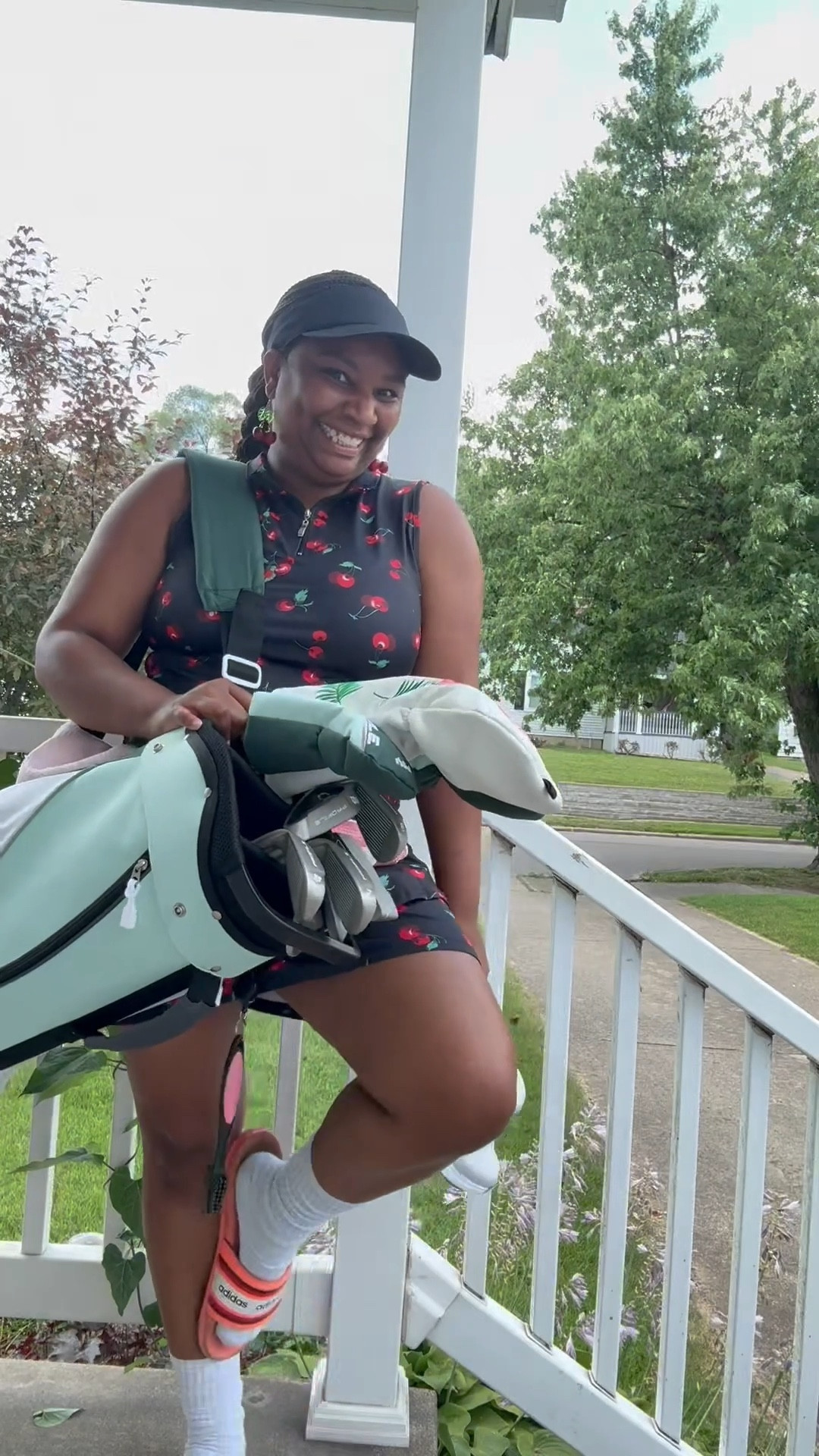 Cherry golf dress, black visor, golf clubs and golf accessories 
