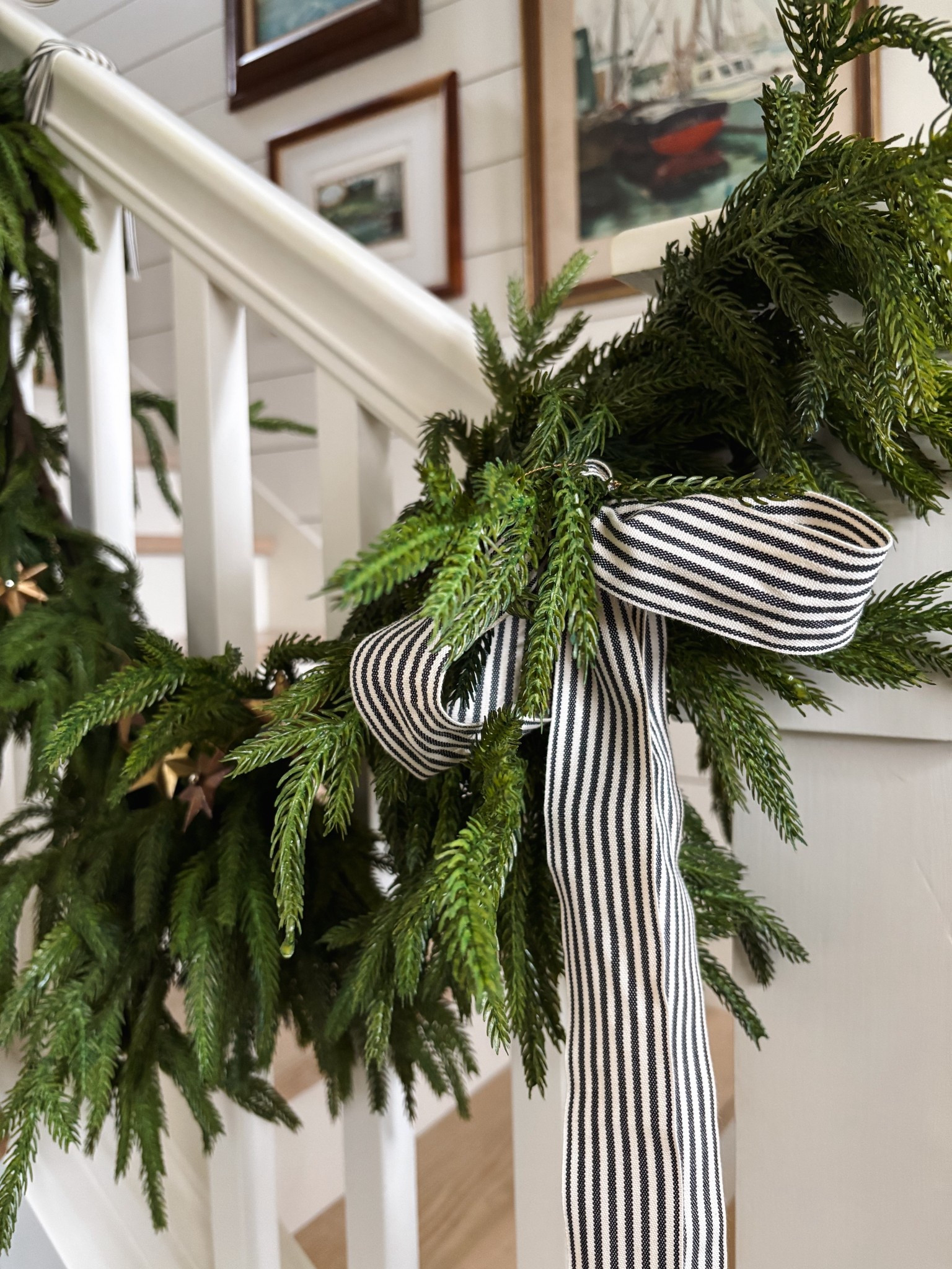 Faux cedar garland and striped black and white ribbon on staircase railing 

#LTKHoliday #LTKSaleAlert #LTKHome