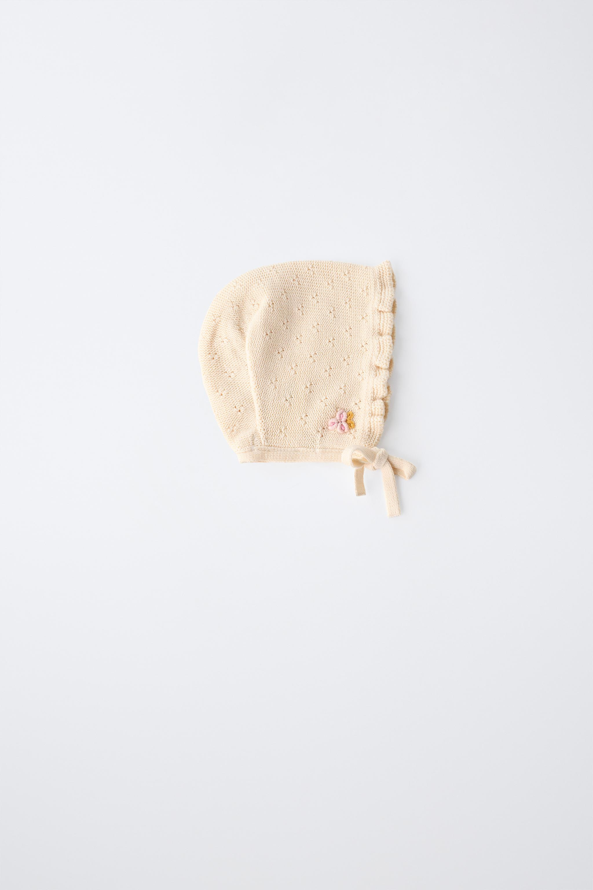 Knit bonnet with adjustable front ties. Features embroidered flower detail and ruffle trim. | Zara US