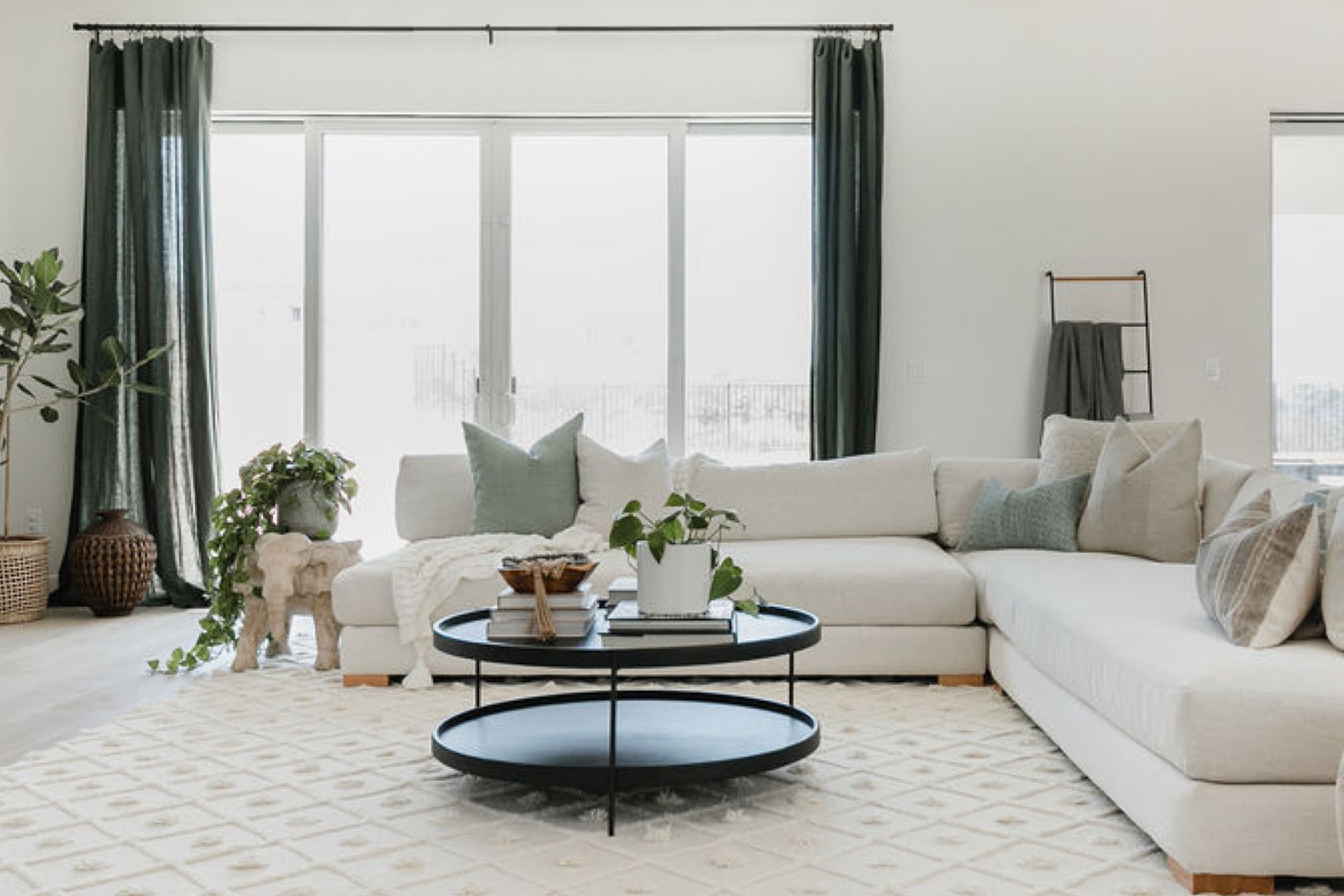 Warm neutral living room with green accents.

Round coffee table, linen curtains in olive, CB2 white linen sectional, curtain rod, large textured area rug in ivory, black woven basket, throw pillows, plants, and a leaning ladder for blankets. 

Living room decor, accent color, home decor, neutral living room. 

#LTKstyletip #LTKFind #LTKhome