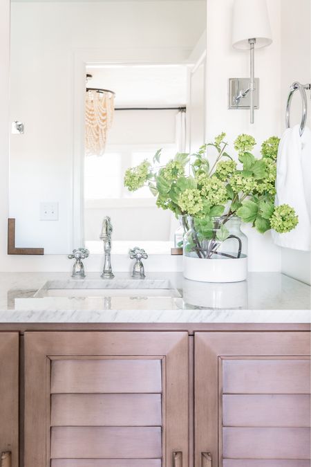 All the details of our small guest bathroom remodel in Omaha! Items include a louvered wood vanity with a Carrara marble countertop, chrome bath faucet, mirror with bracket corners, paint dipped vase with faux viburnum stems, silver wall sconces, and chrome bathroom hardware. See even more details here: https://lifeonvirginiastreet.com/small-guest-bathroom-remodel-reveal/

.
Amazon home decor, target home, target finds, mcgee and co mirror, studio mcgee mirrors, amazon faucets, amazon bathroom accessories, bathroom vanity lighting, wall sconce, bathroom faucet, bathroom flooring, bathroom ideas, bathroom inspiration, amazon bathroom, bathroom hardware, bathroom accessories, bathroom remodel, cement tile, wood vanities, white bathroom, wall sconces, chrome light fixtures 

#ltksalealert #ltkhome #ltkfindsunder50 #ltkfindsunder100 #ltkstyletip #ltkseasonal #ltkkids #ltkfamily 

#LTKSeasonal #LTKSaleAlert #LTKHome