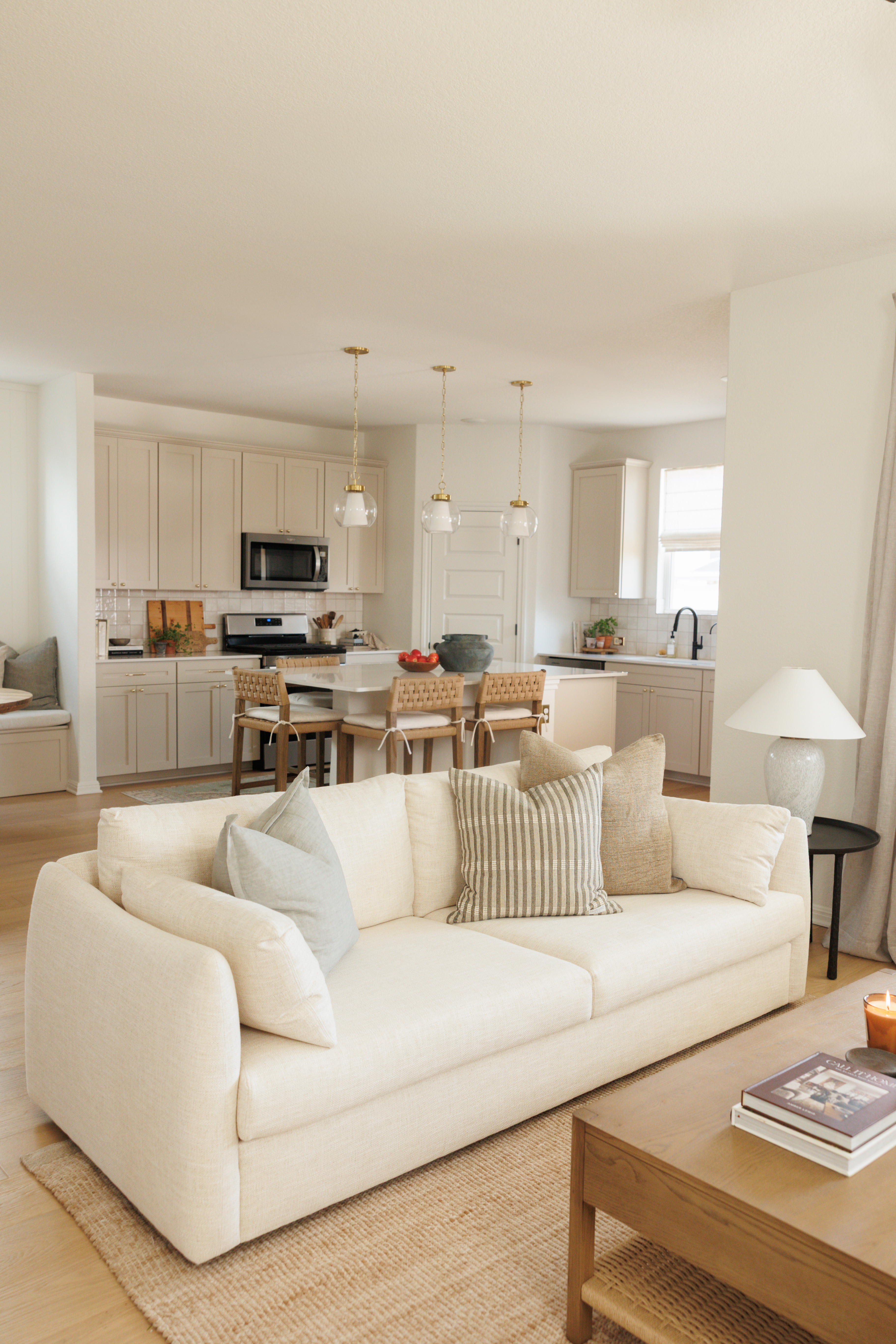 We made this open-concept living space feel more cozy with a timeless white sofa, wool rug, and light wood coffee table. Woven counter stools and brass pendants brought some much-needed warmth to the kitchen! 

 #LTKHome