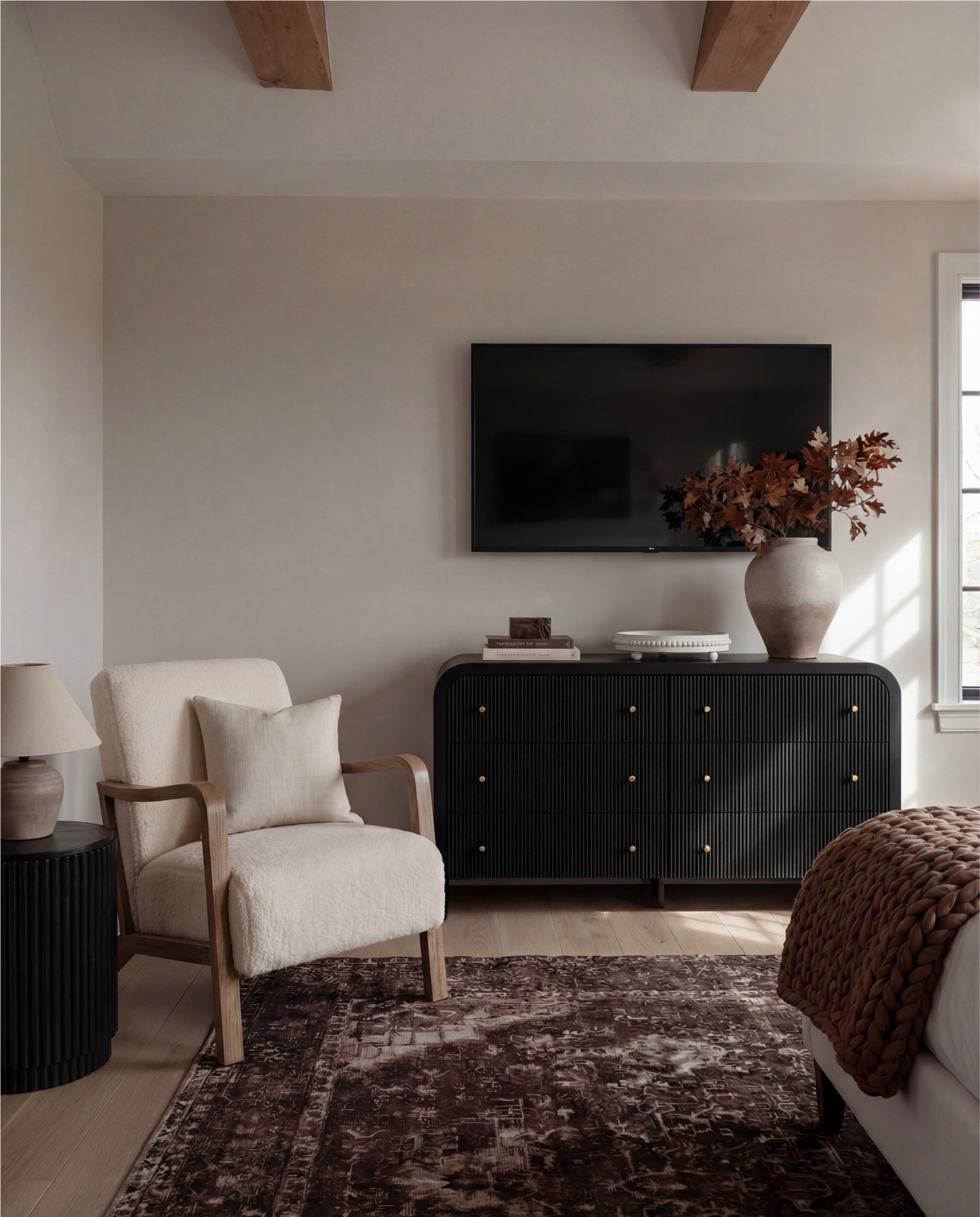 This bedroom feels warm, layered, and quietly refined. The soft upholstered bed keeps the space light and serene, while rich wood tones, earthy textiles, and vintage-inspired accents add depth and contrast. Sculptural lighting, warm brass details, and cozy textures create a balance between elegance and comfort — a space that feels elevated yet deeply livable.

The styling leans into warm neutrals and organic materials — chunky knits, aged woods, soft linen layers, and curated decorative moments that give the room a collected, timeless atmosphere.

Shop the Look:
• White upholstered wingback bed frame
• White cotton duvet cover + pillow shams
• Textured throw pillows (rust + black patterned)
• Chunky knit throw blanket (warm brown)
• Vintage-style brown area rug
• Dark wood nightstands with brass knobs
• Ceramic table lamp (neutral glaze)
• Brass globe wall sconces
• Framed floral artwork (muted tones)
• Arched brass wall mirrors
• Upholstered bench at foot of bed (camel brown)
• Cream accent chair with wood arms
• Black fluted dresser with brass pulls
• Round black fluted end table 
•Fecor books 
• Large ceramic floor vase (earthy clay tone)
• Decorative wood bead garland
• Sheer white curtain panels
•Round decor bowl tray 
•Wood jewellery box 
•Terracotta bowl 

#LTKSaleAlert #LTKHome